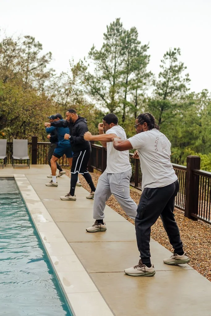 Group of people exercising outdoors near a swimming pool, practicing aerobic moves.