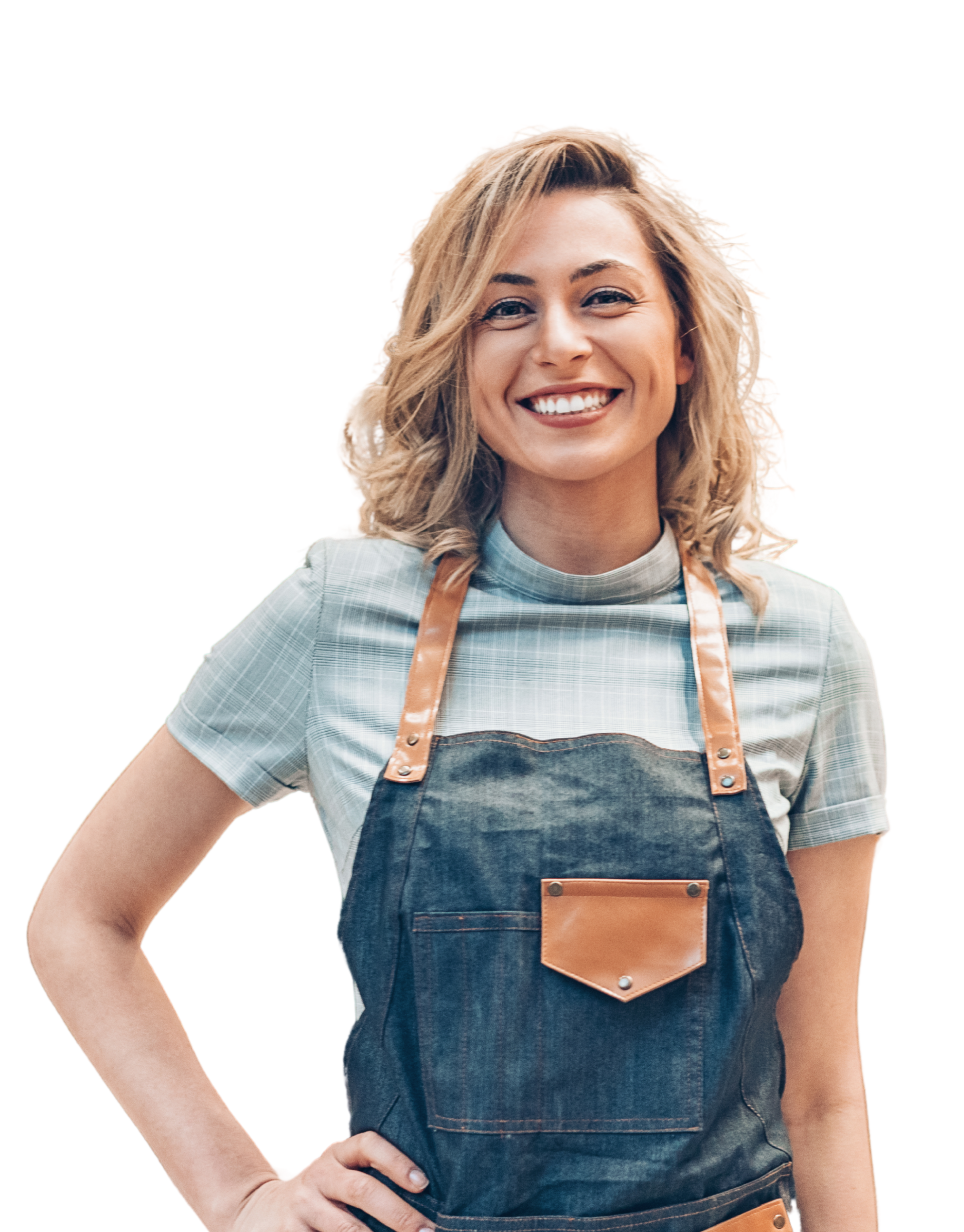 A smiling woman with blond hair wearing a plaid shirt and denim apron stands with one hand on her hip.