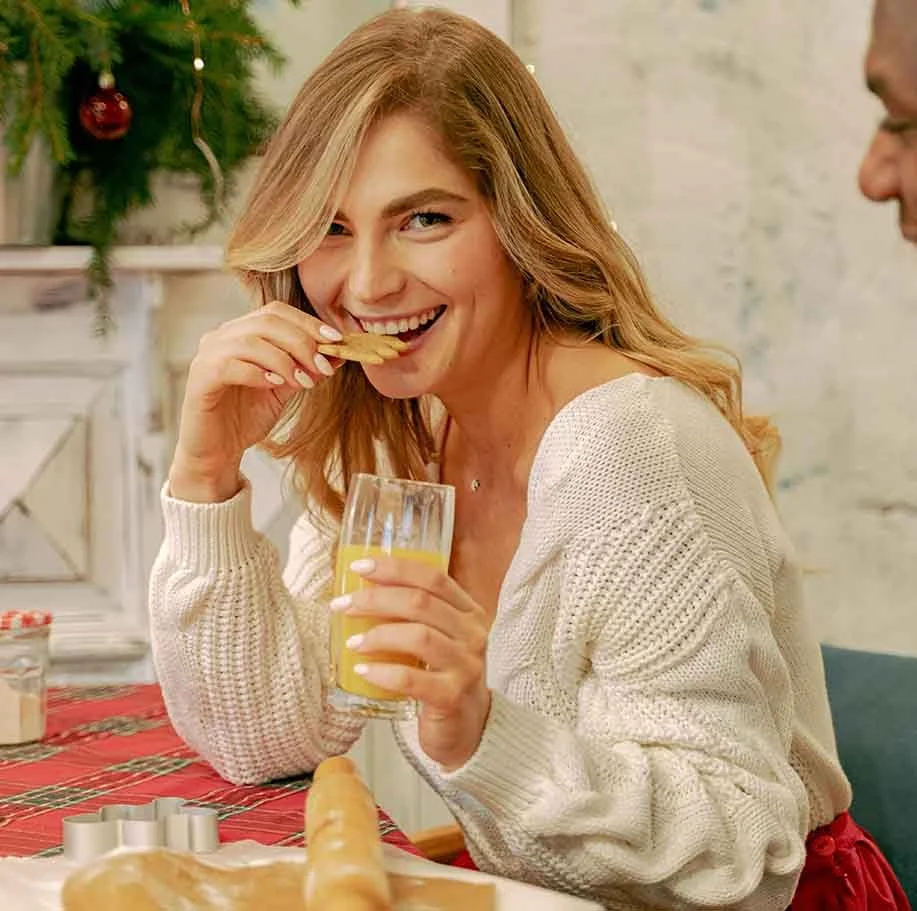 woman grinning and indulging in eating holiday cookies
