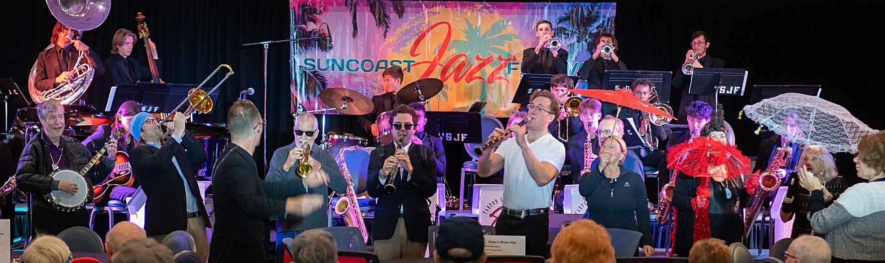 Festival goers dancing with parasols with musicians performing Big Easy Flavored Jazz at the Suncoast Jazz Festival