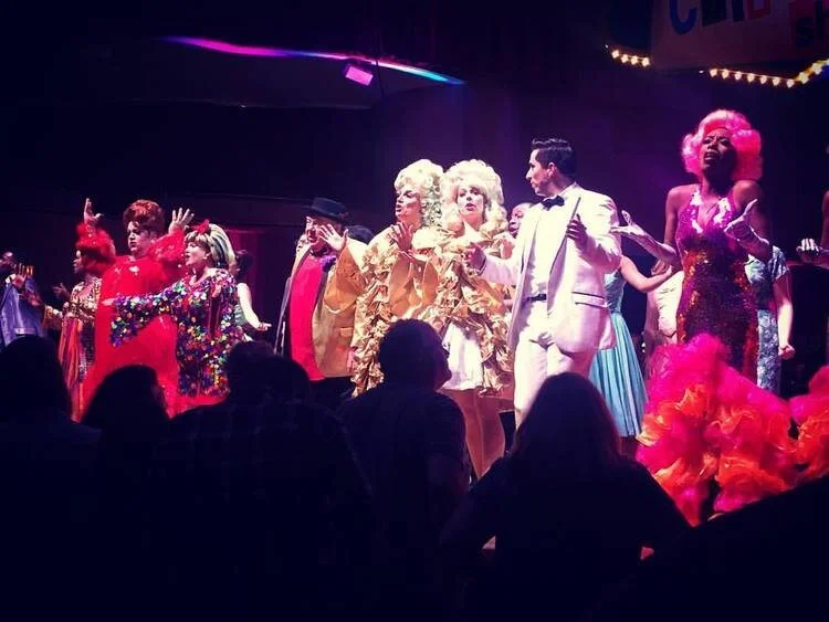 Performers on stage wearing colorful and elaborate costumes, performing in front of an audience.