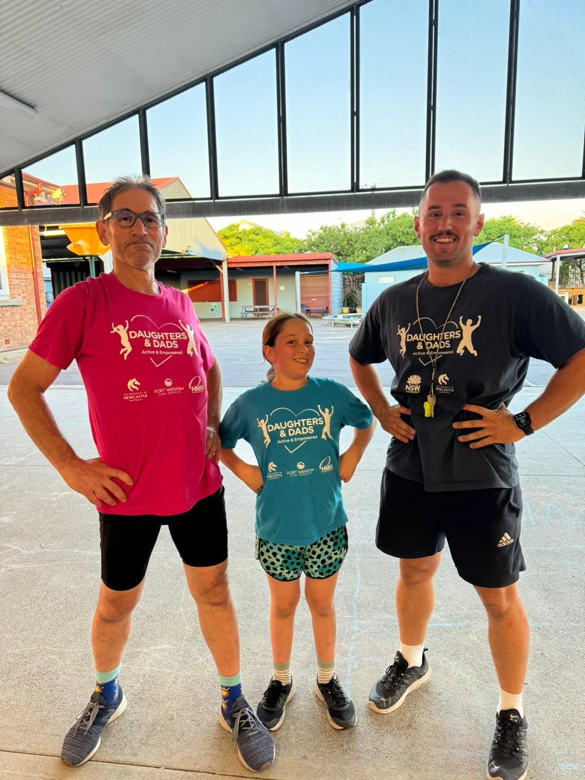A program facilitator standing with a daughter and dad in a school