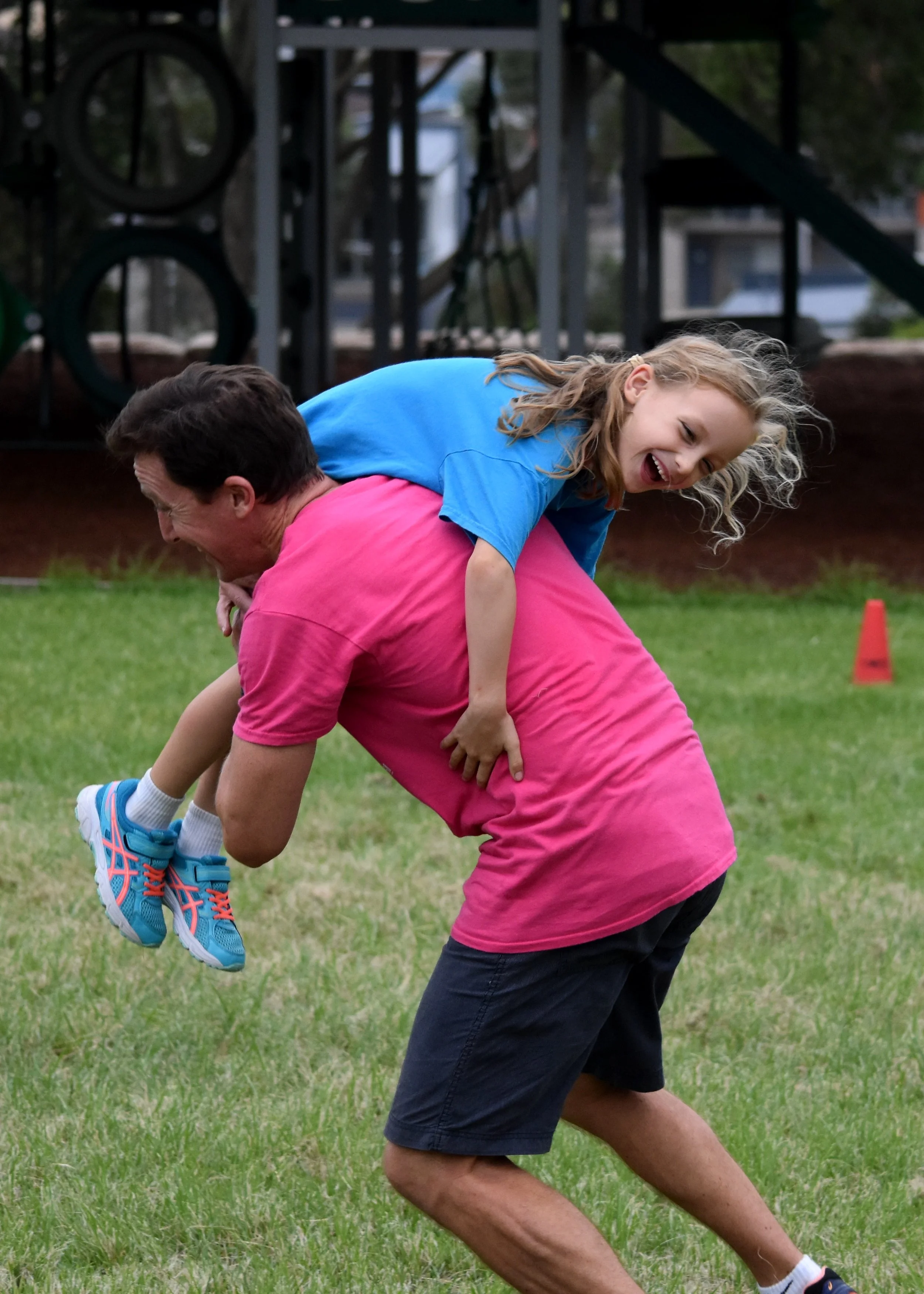 A dad carrying his laughing daughter over his shoulder