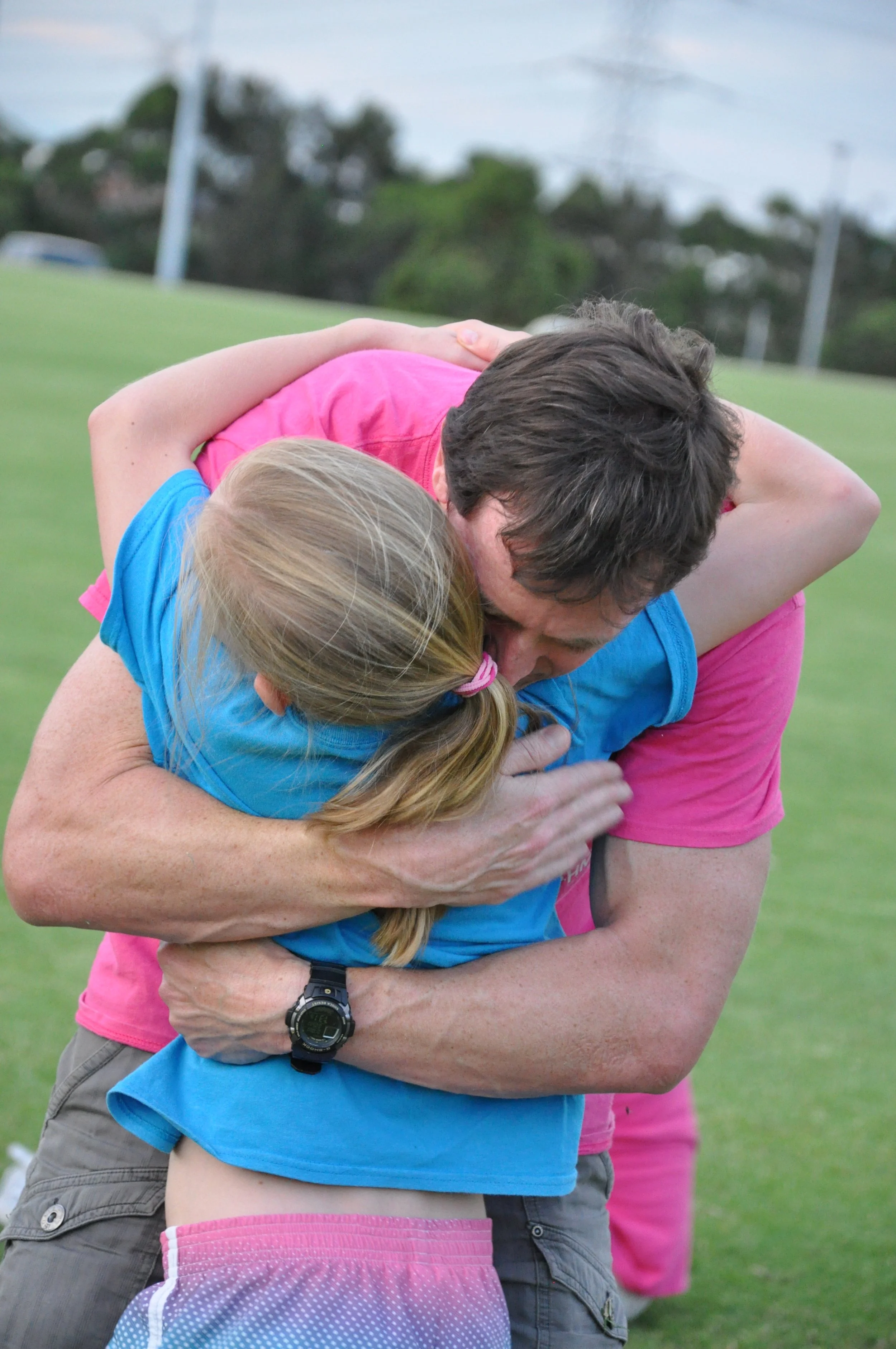 A daughter hugging their dad around his neck