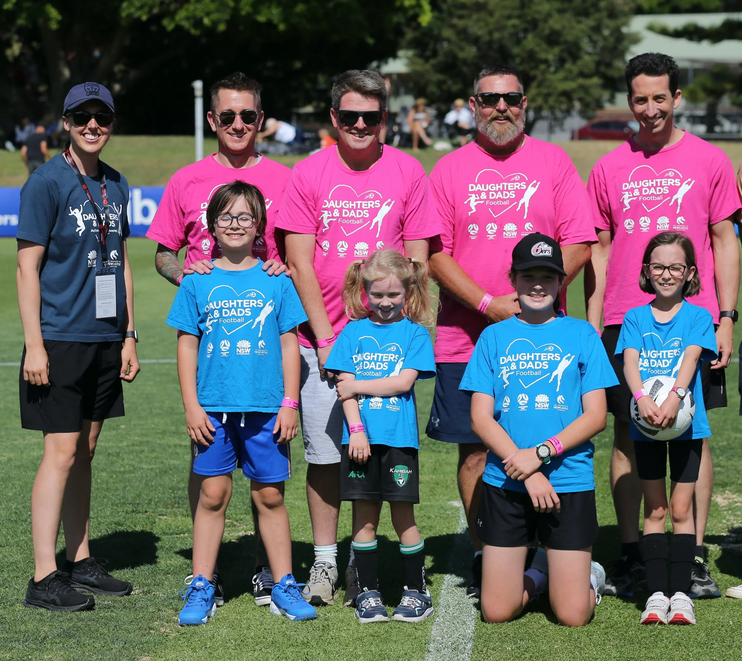 A program facilitator standing with four pairs of daughters and dads