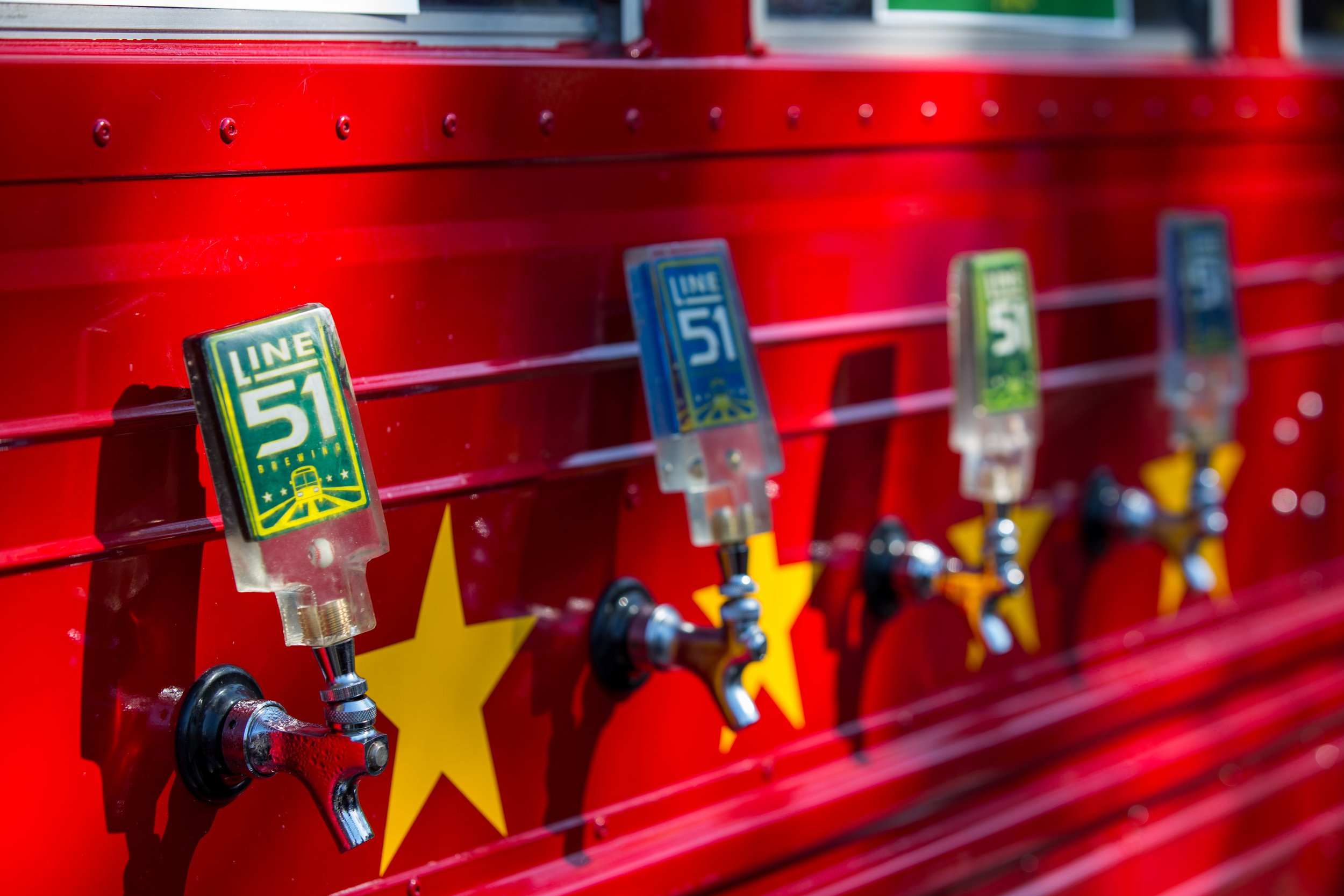A red water dispenser with multiple taps, each with a tap handle featuring a Metro Line 51 sign and yellow star symbols.