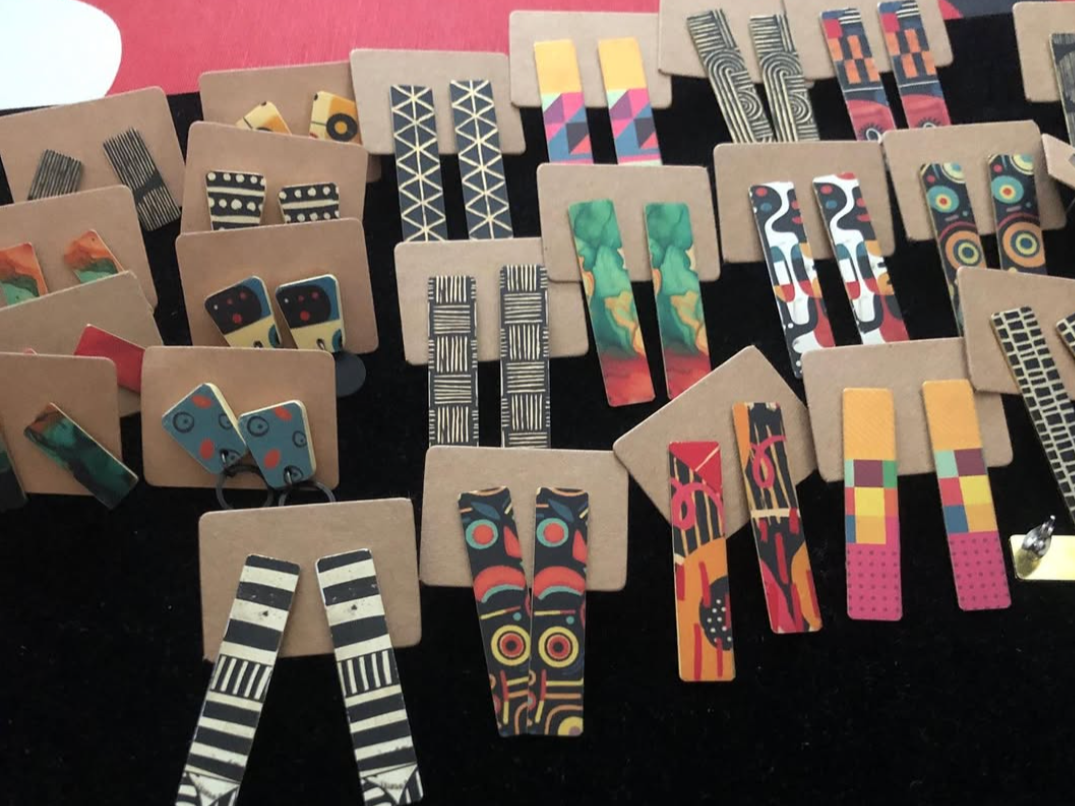 Colorful patterned earrings displayed on cardboard backing.