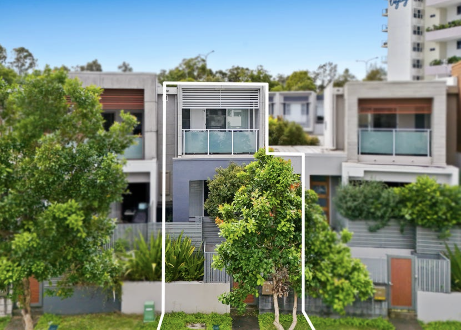A modern townhouse with large windows and balconies, surrounded by trees and greenery in a suburban neighborhood.
