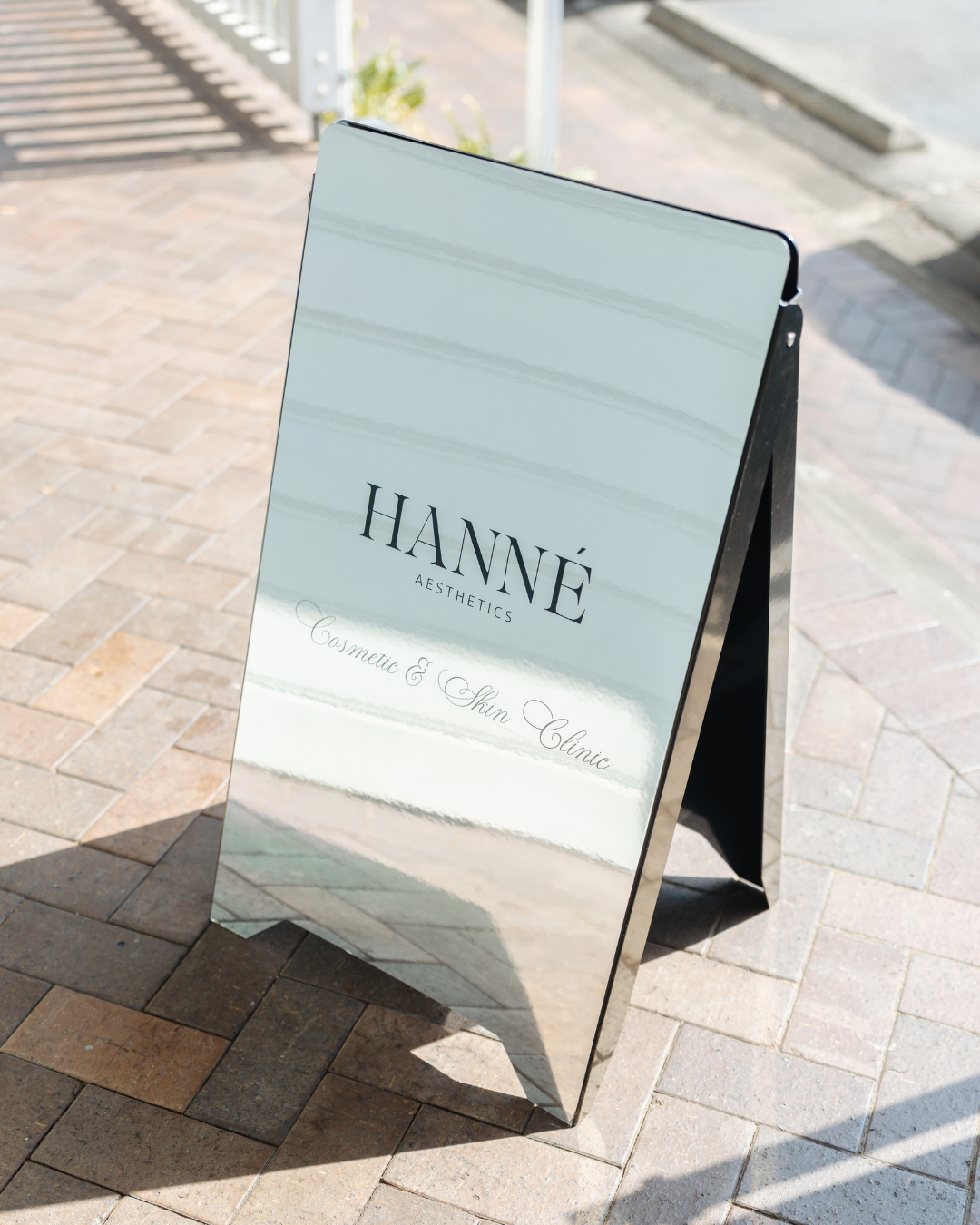 A sidewalk chalkboard sign outside a cosmetic and skin clinic called HANNÉ AESTHETICS.