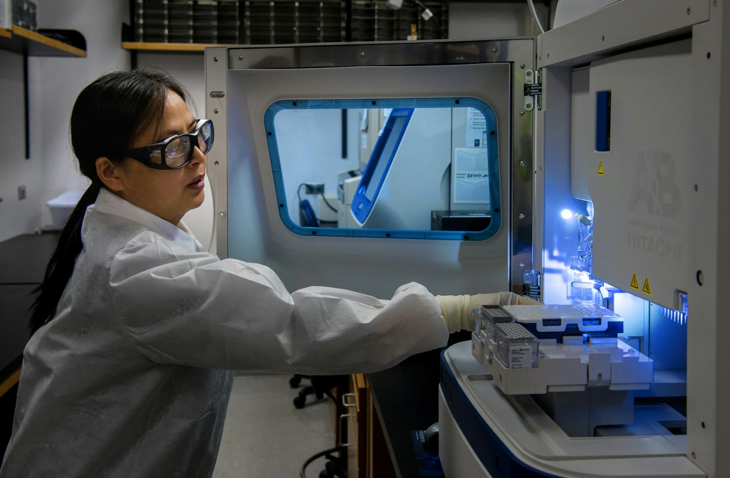 Female lab assistant wearing white coat and protective eye wear in a laboratory