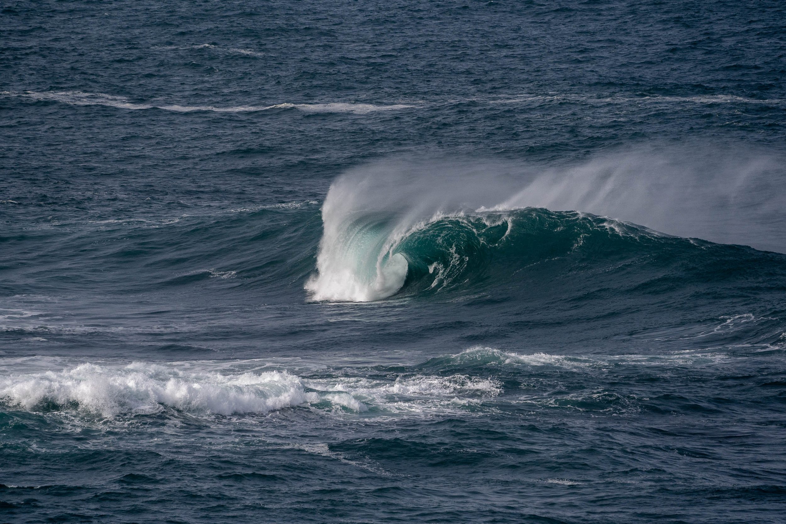 Grande vague océanique se brisant avec des embruns blancs sur une mer agitée