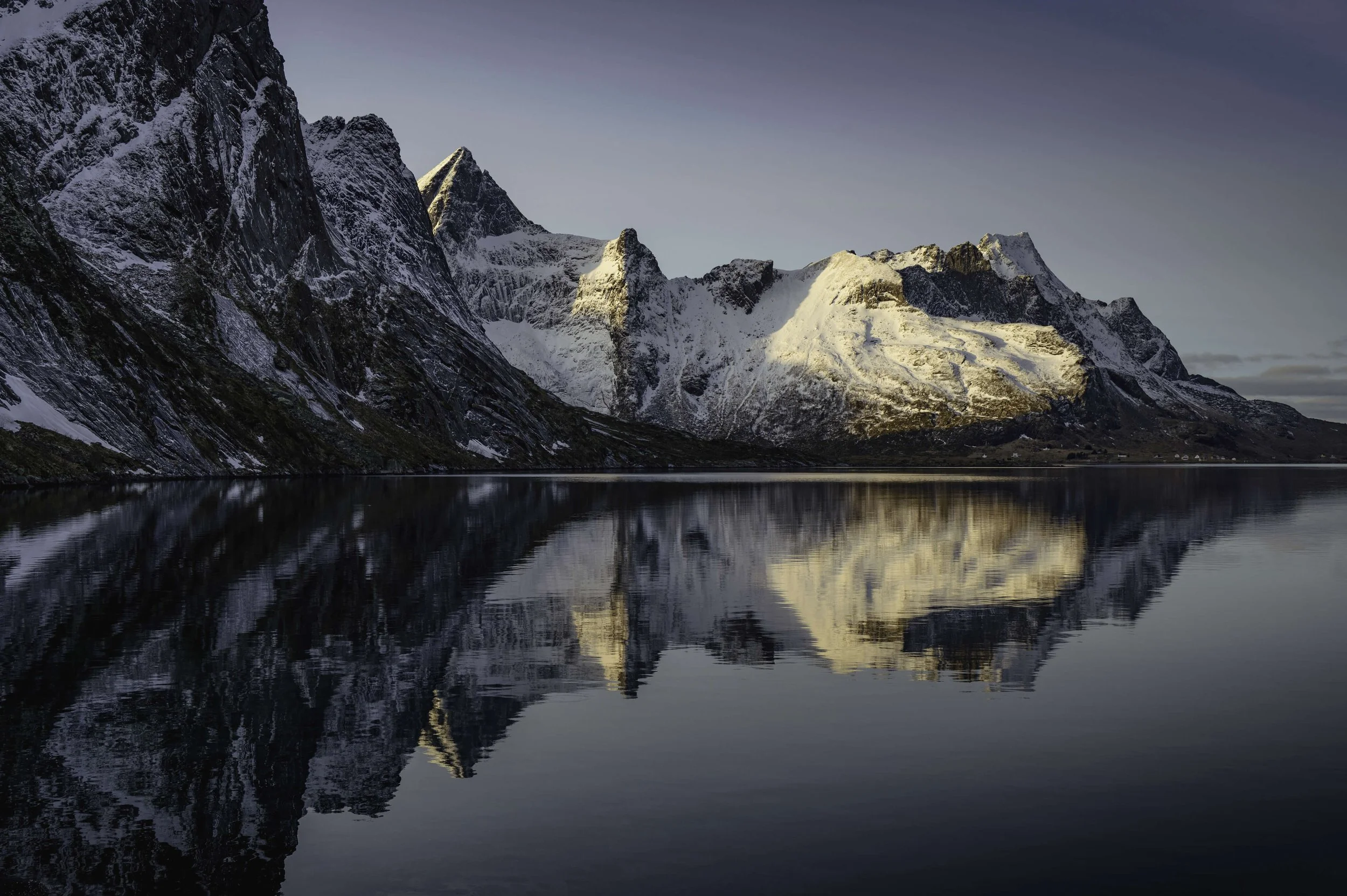 Montagnes enneigées se reflétant dans un lac calme au crépuscule.