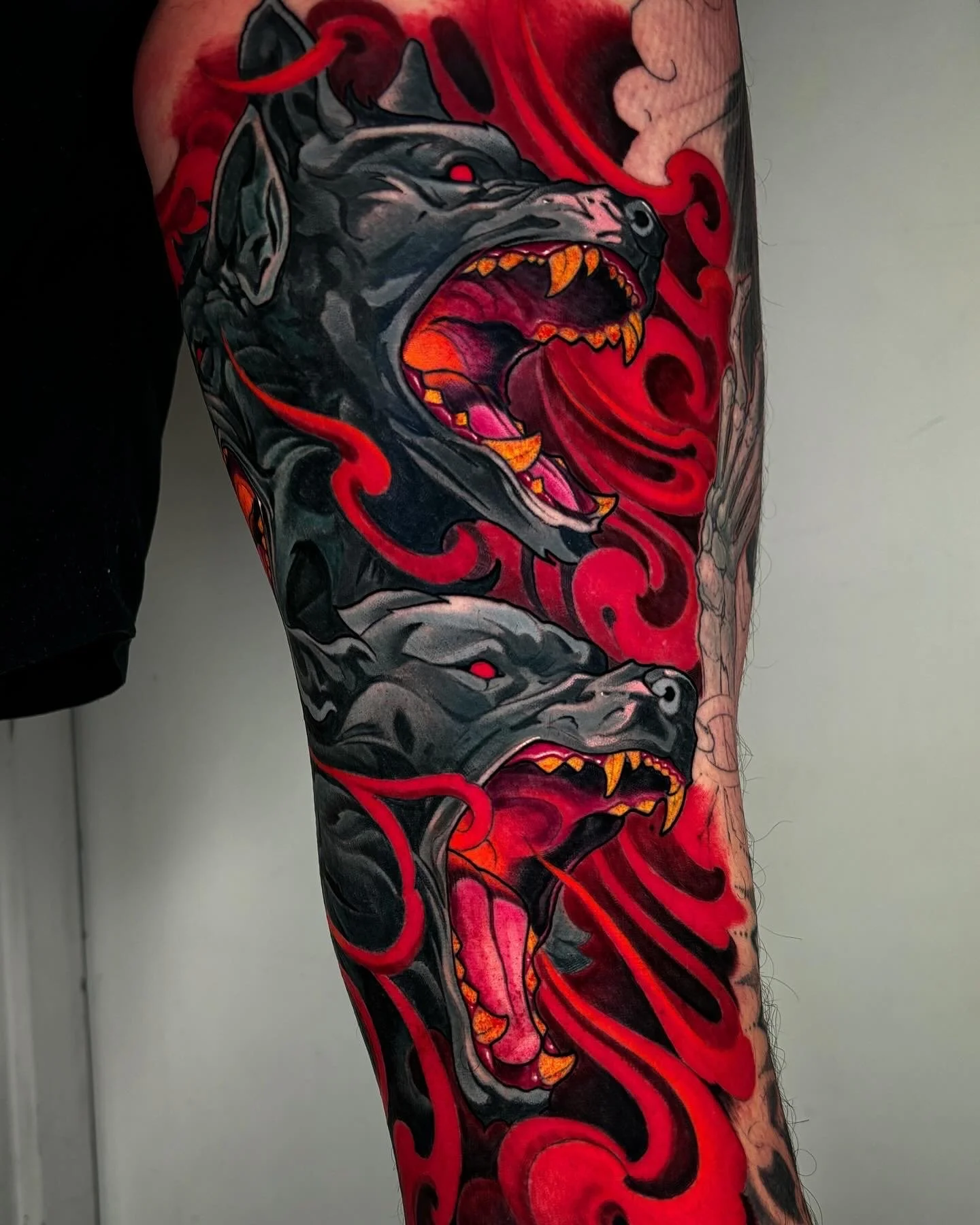 Two snarling dark animal heads with flowing red shapes by Nicklas Wong, tattoo artist in Northcote, Melbourne