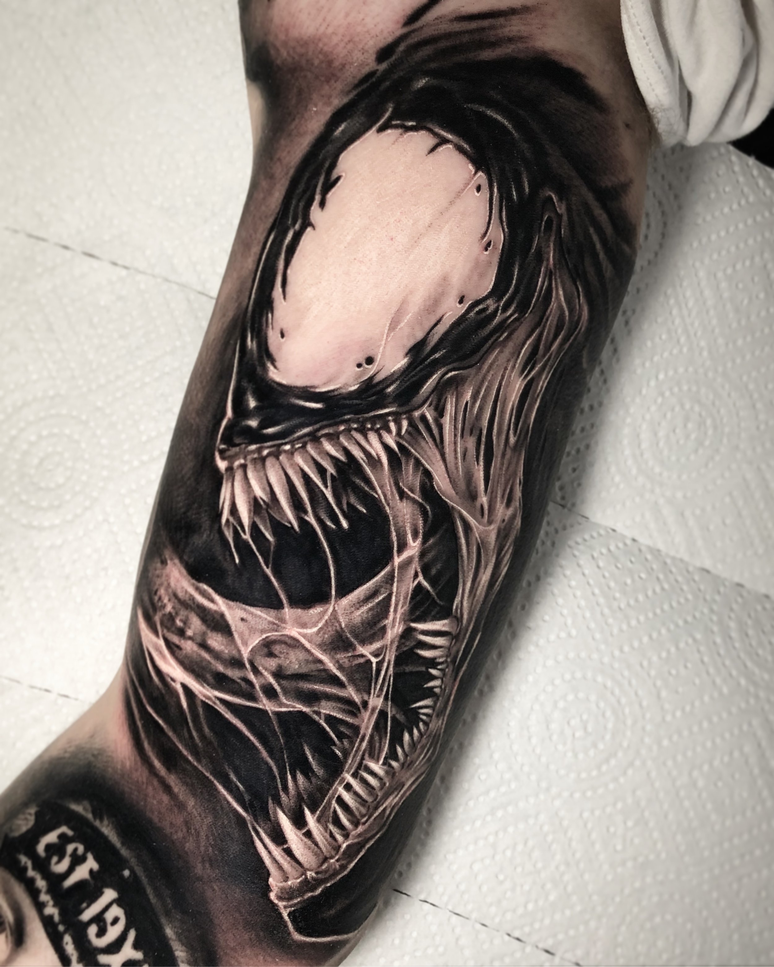 Black and grey Venom tattoo with sharp teeth and textured shading by Nicklas Wong, tattoo artist in Northcote, Melbourne