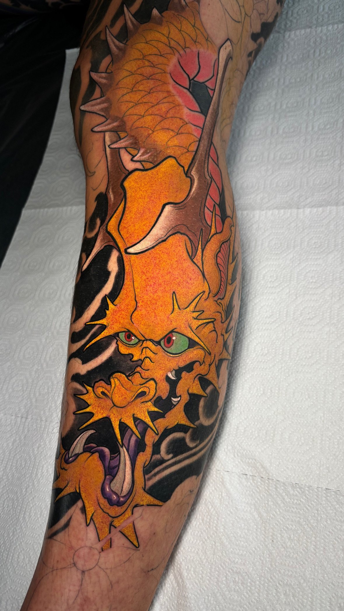 Orange Japanese dragon tattoo with dark background details by Nicklas Wong, tattoo artist in Northcote, Melbourne