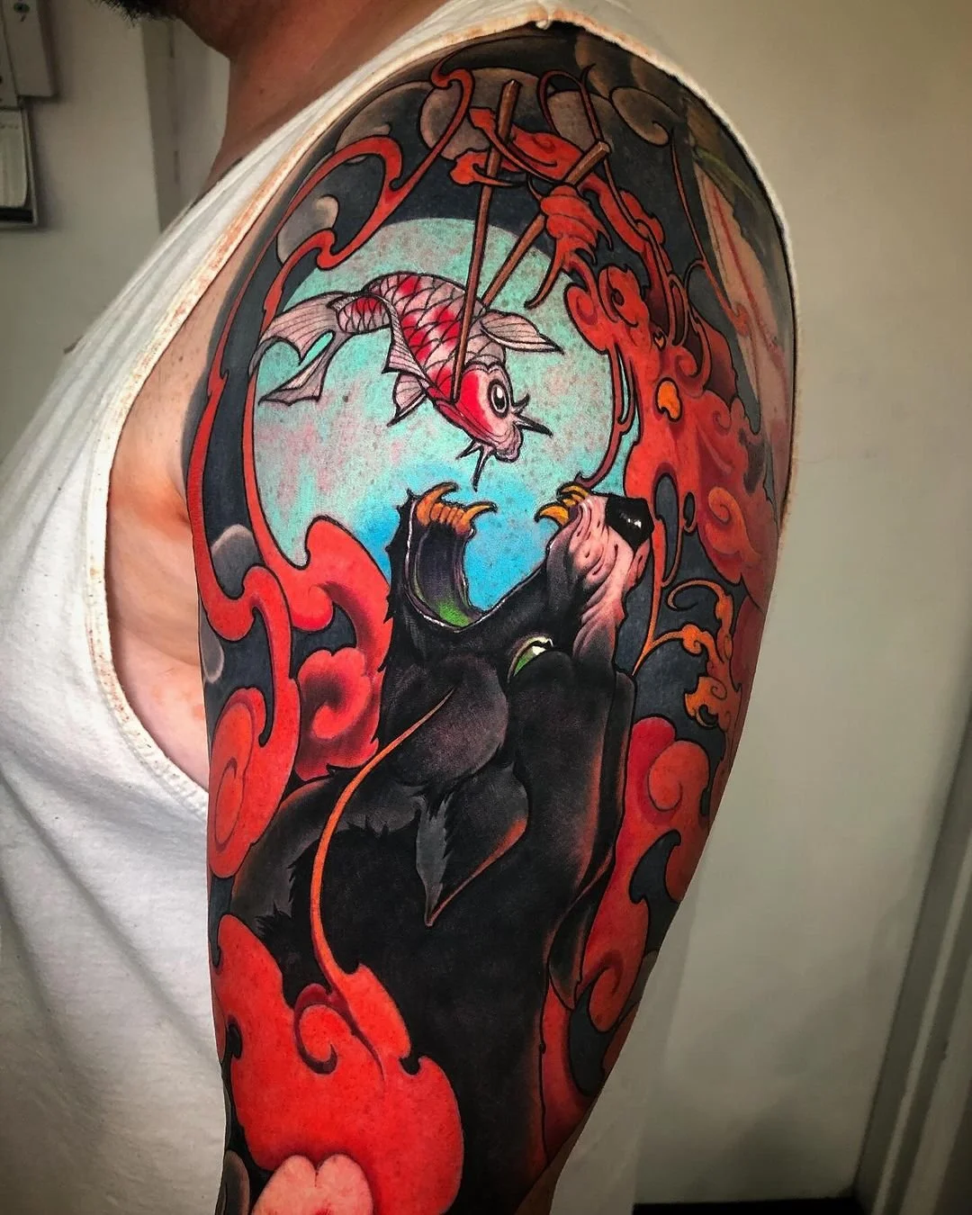 Dark fantasy upper-arm tattoo with a blue moon and red flame shapes by Nicklas Wong, tattoo artist in Northcote, Melbourne