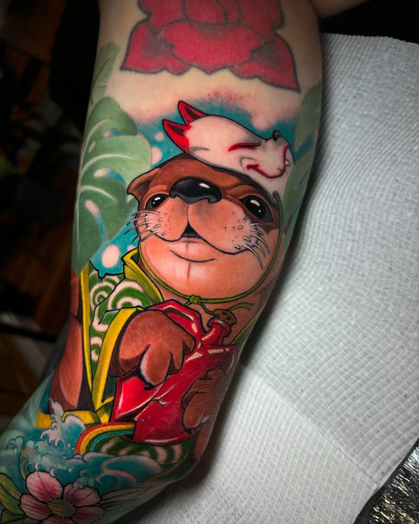 Neo-traditional otter tattoo with red clothing and flowers by Nicklas Wong, tattoo artist in Northcote, Melbourne