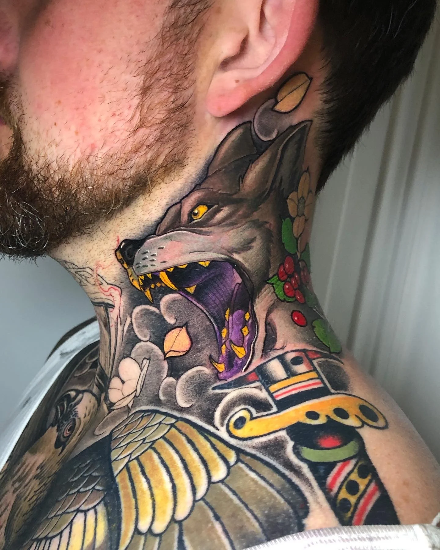 Snarling wolf neck tattoo with dark shading and colour details by Nicklas Wong, tattoo artist in Northcote, Melbourne