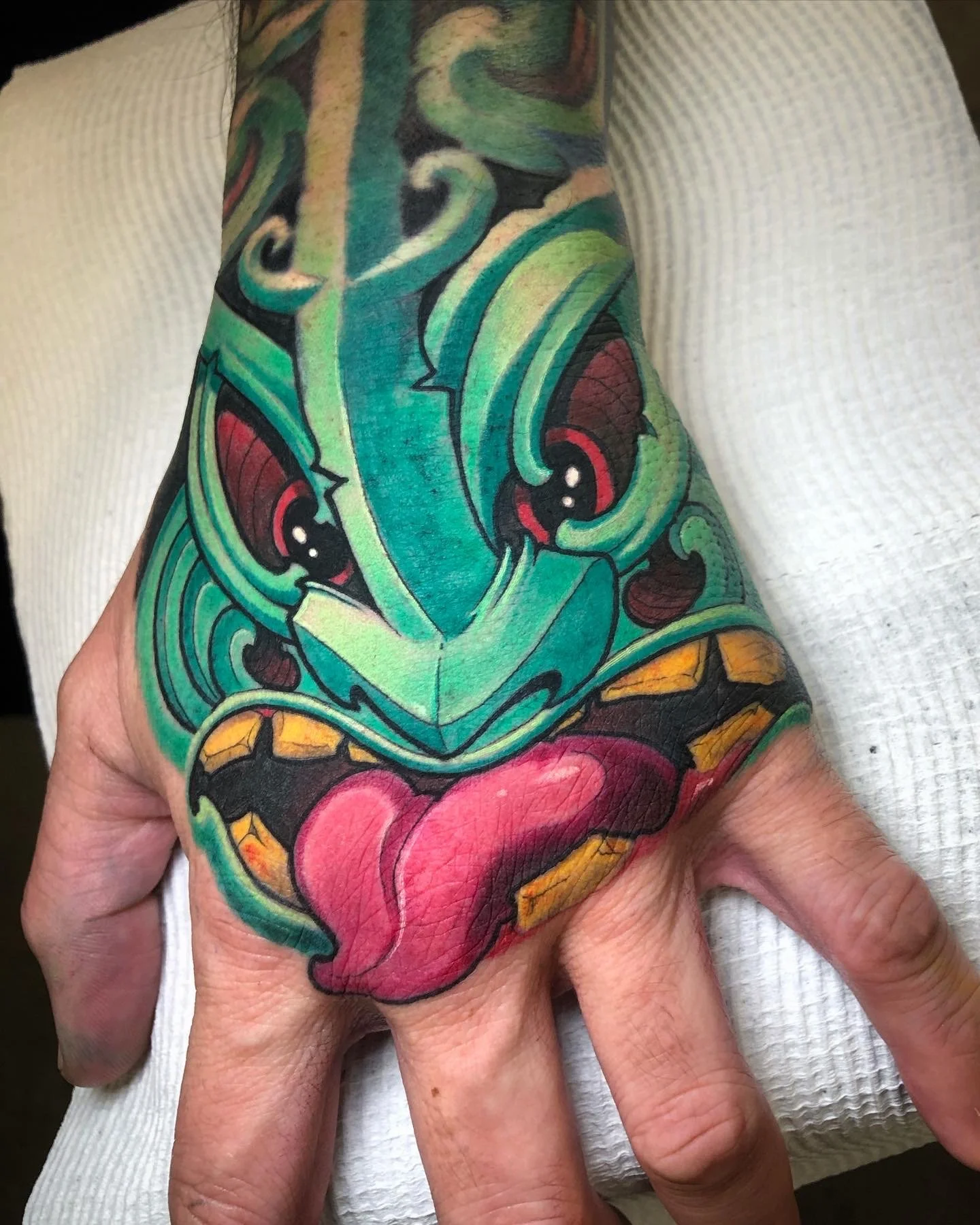 Green monster hand tattoo with red eyes and a pink tongue by Nicklas Wong, tattoo artist in Northcote, Melbourne