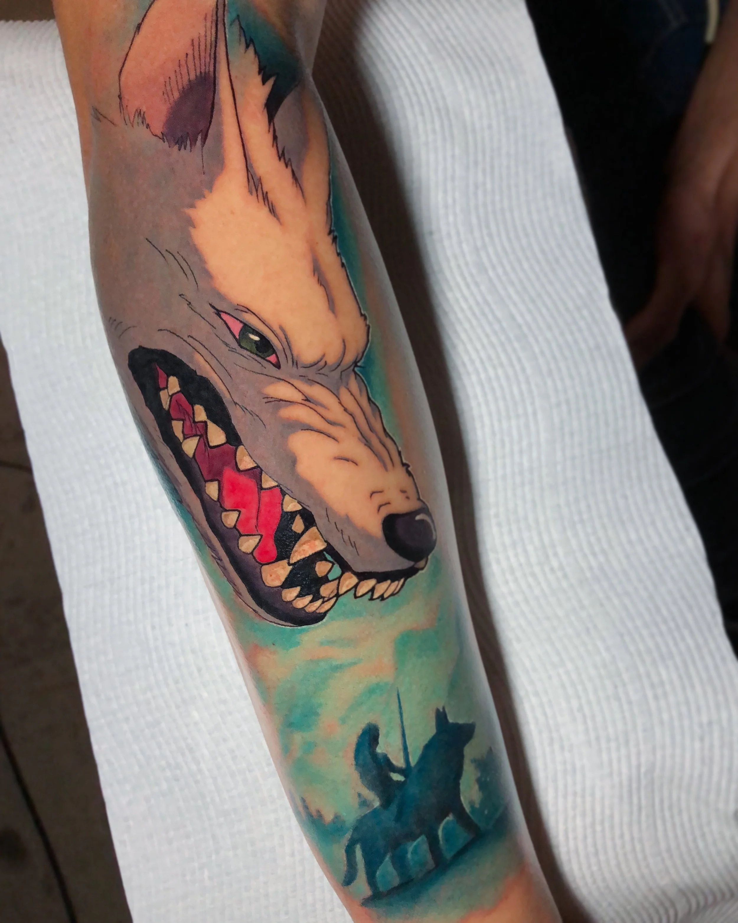 Anime-inspired snarling wolf forearm tattoo with a blue-green background by Nicklas Wong, tattoo artist in Northcote, Melbourne
