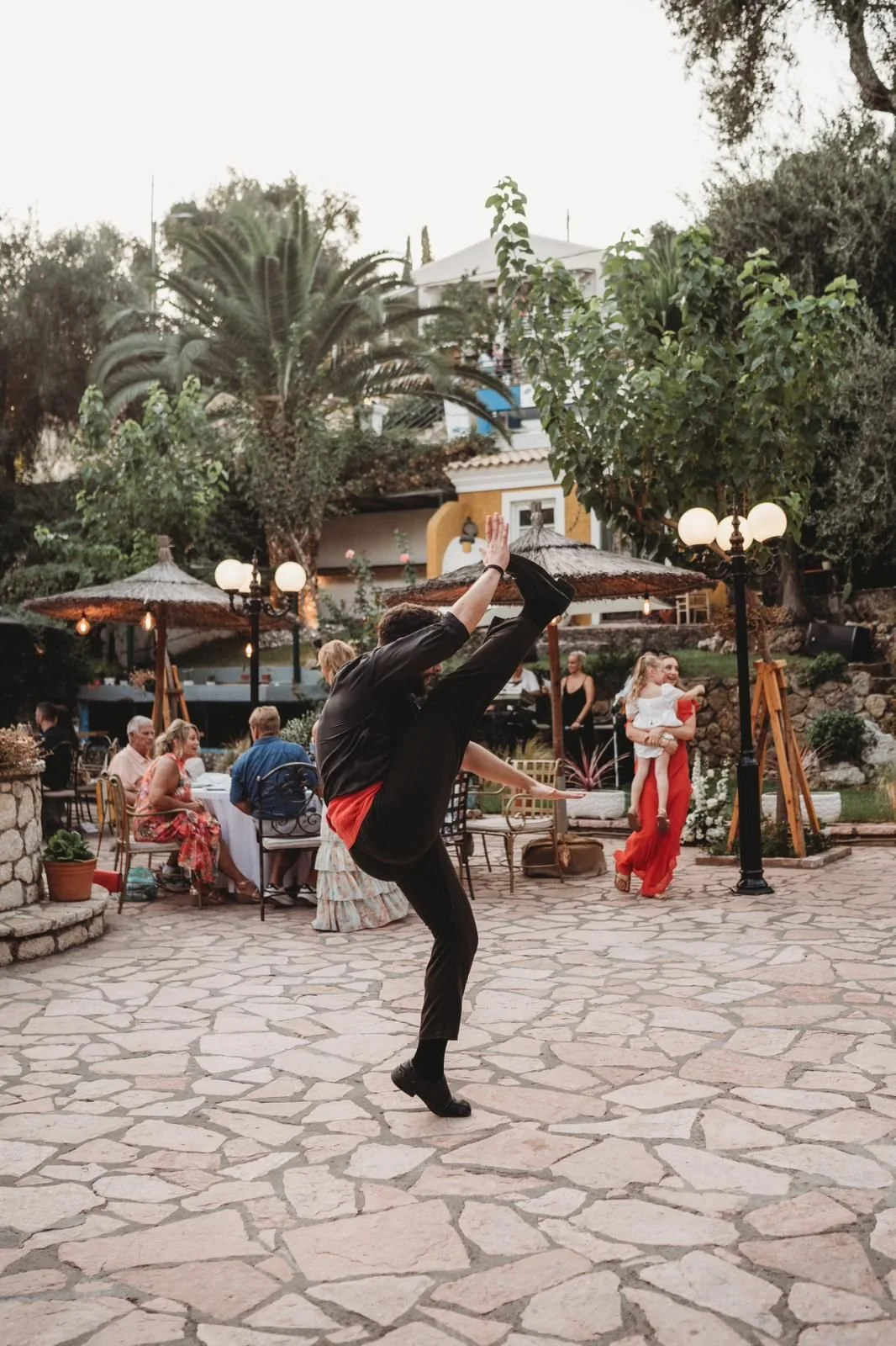 A bride and groom holding hands as they walk down a stone pathway in a lush garden during their wedding celebration.