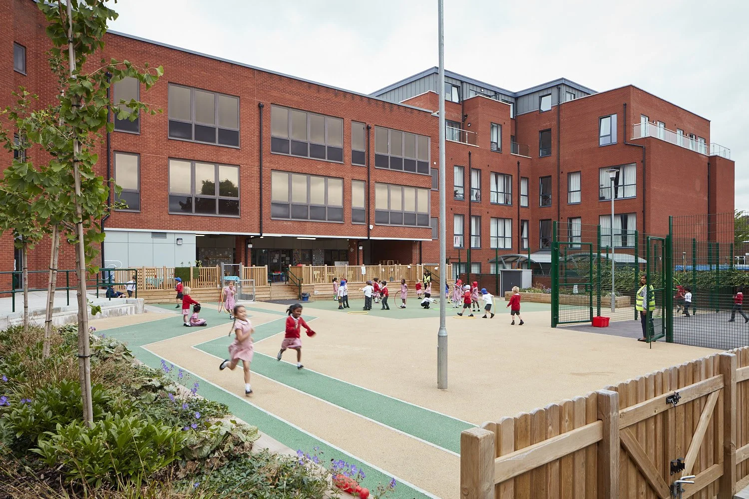 children play outside in the playground in front of the main school buildings