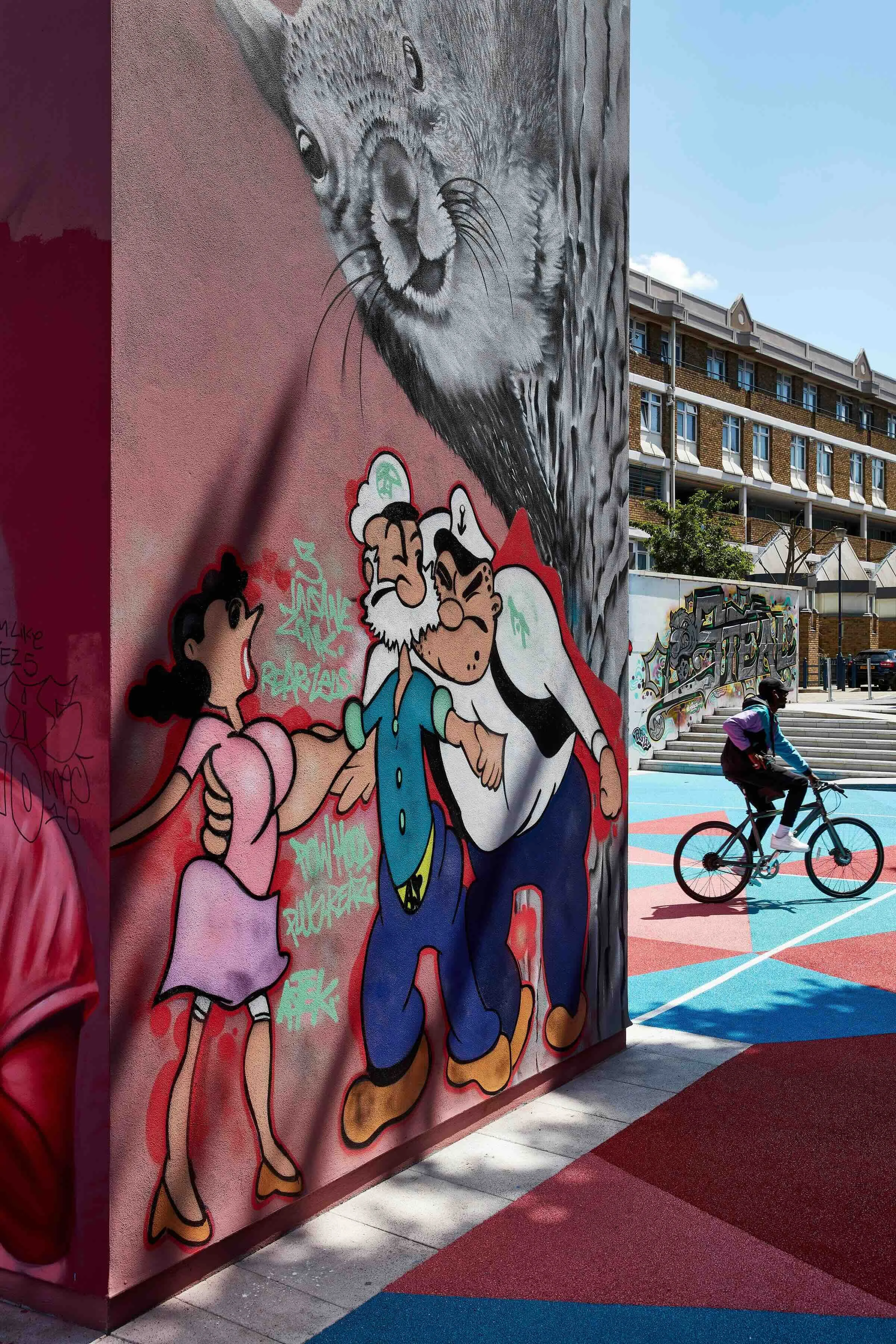 Popeye and Olive street art with cyclist in the background