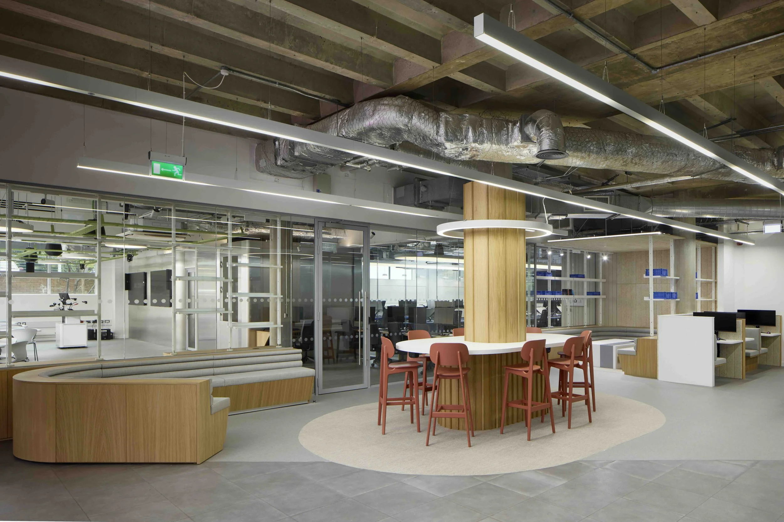 Rock Townsend Architects LLP — The Games Hub, Harrow Campus, University Of Westminster - Modern teaching area with wooden furniture, a circular bar table with chairs, glass-walled m