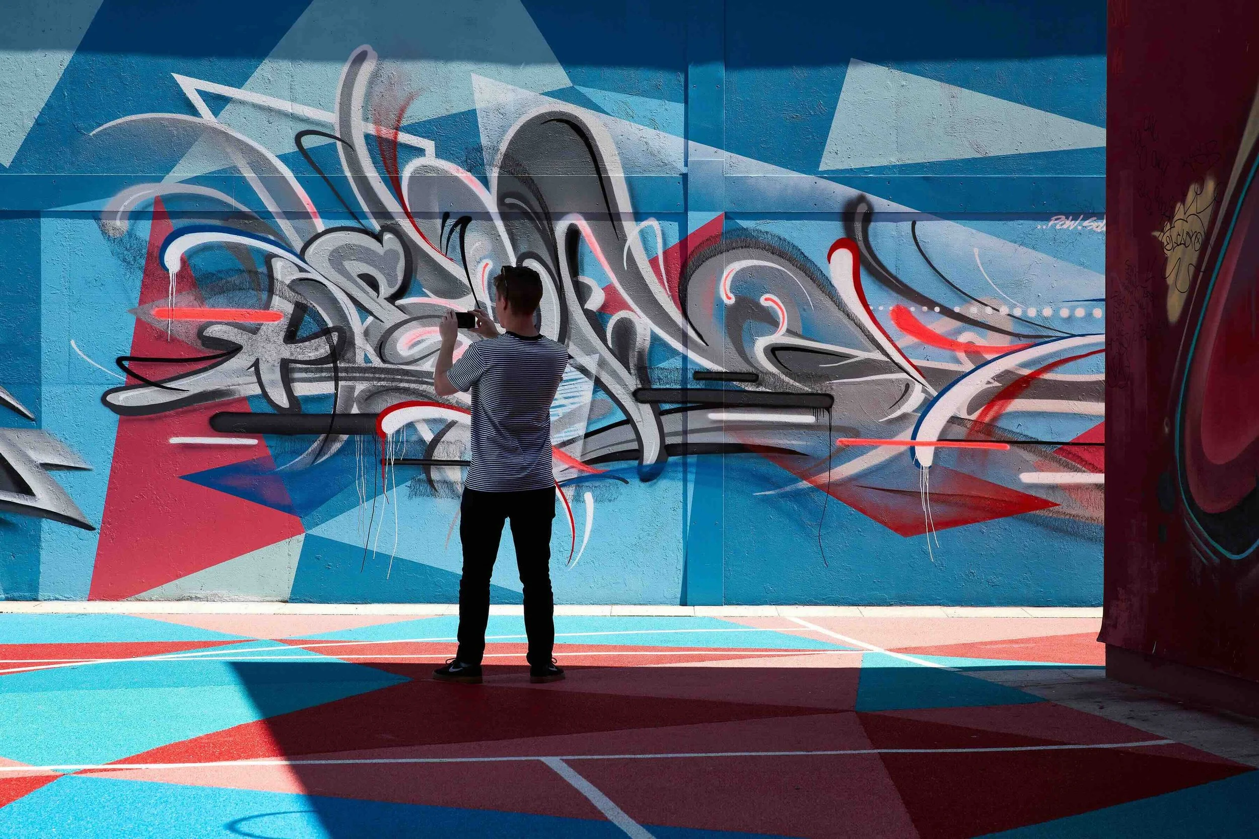 man taking photograph of street art on the walls