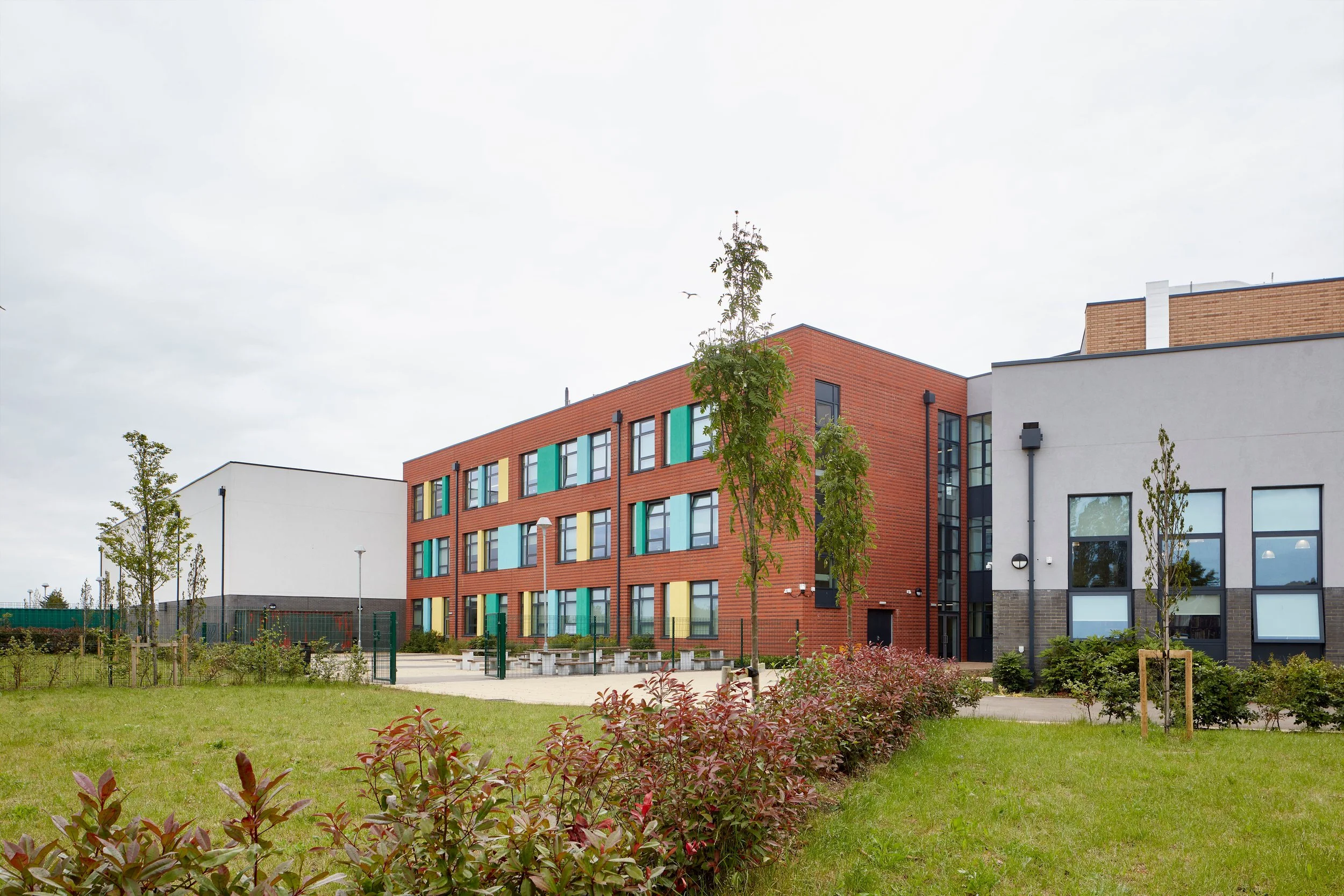 view across the landscaped playround and break-out spaces towards the red brick block