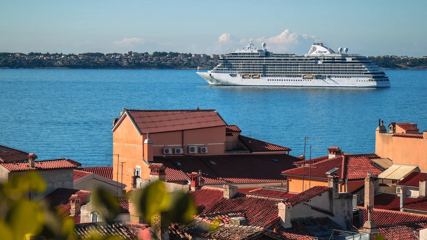 A floating city rests on the horizon, anchored just beyond Piran’s timeless walls — where Venetian whispers meet the sea. The cruise ship lingers like a dream paused mid-sentence, caught between journeys, watching the old town shimmer in
