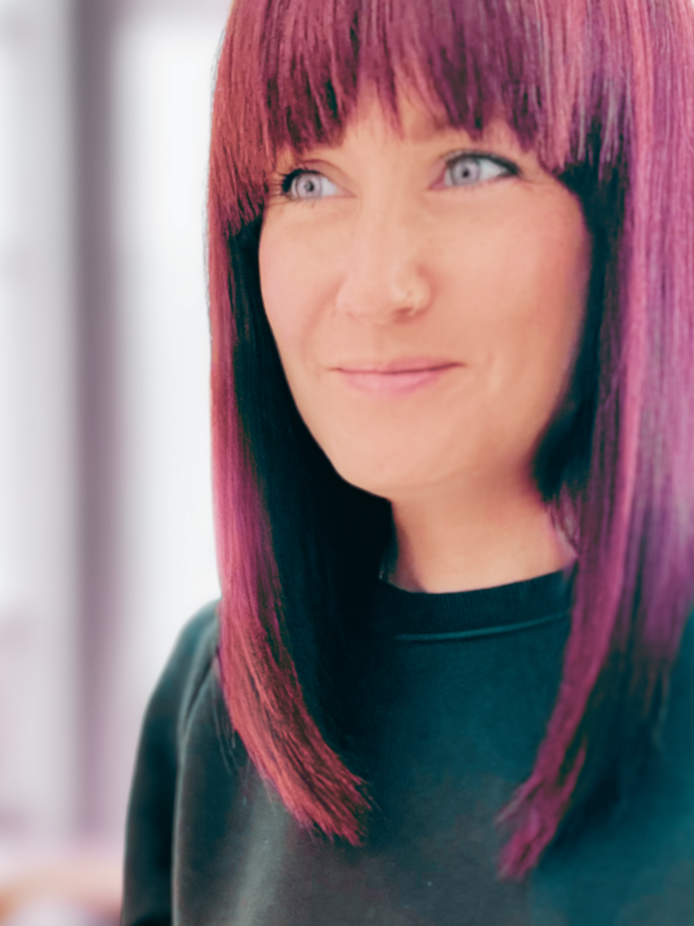 Close-up of Jules, a woman with straight, shoulder-length red hair, wearing a dark blue top, smiling softly.