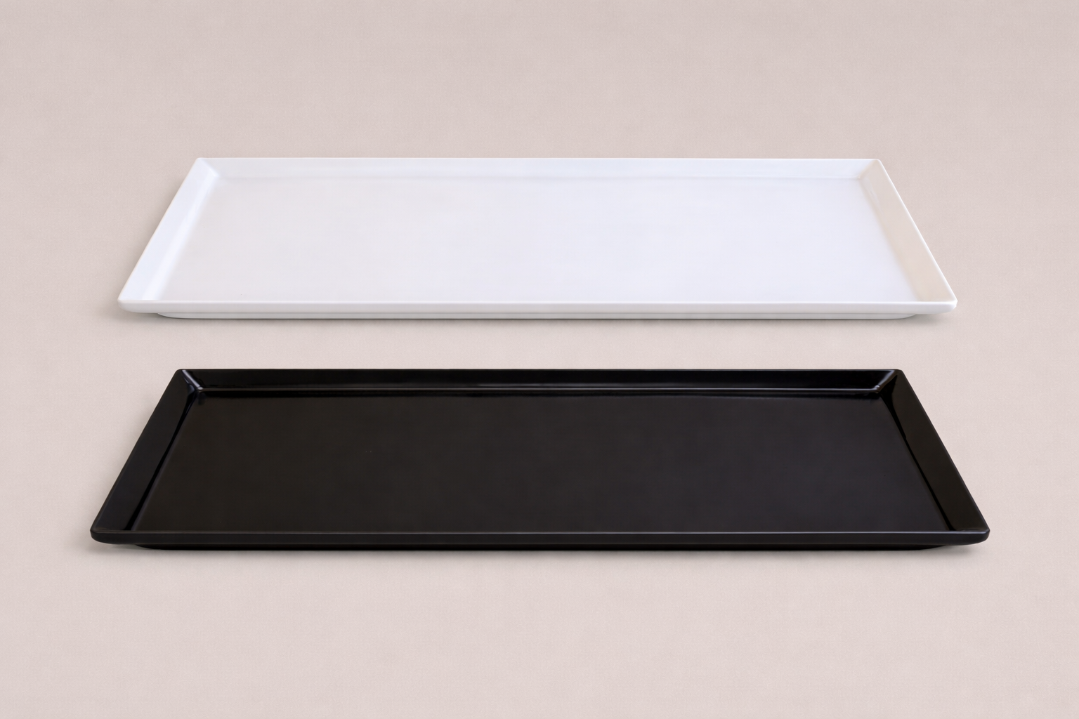 Twee rechthoekige dienbladen, een wit en een zwart, liggen op een lichte ondergrond.
