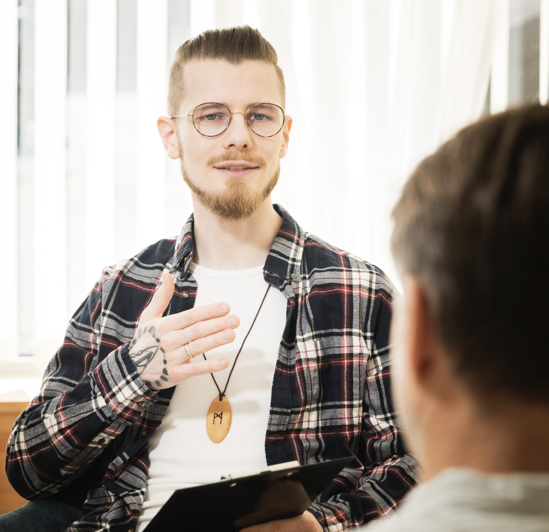 Raphael Komanns im Gespräch, während er eine Hand auf seine Brust legt und ein Notizheft hält.
