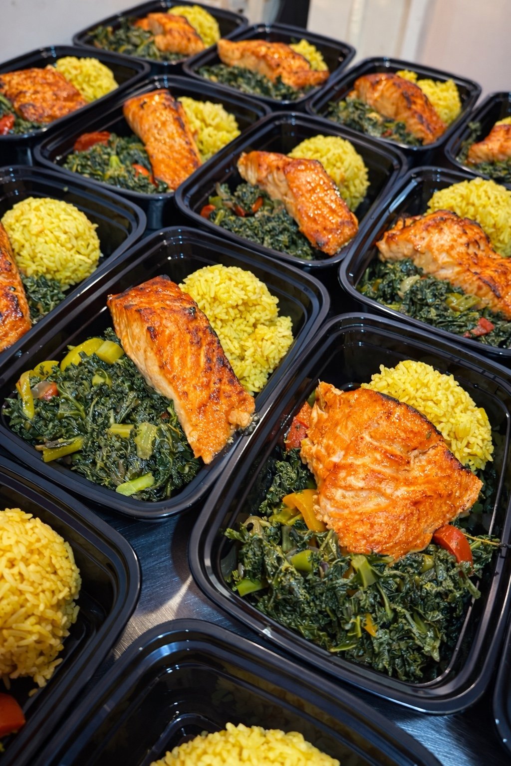 Salmon with rice and greens in individual meal trays, prepared by Socialized Catering.
