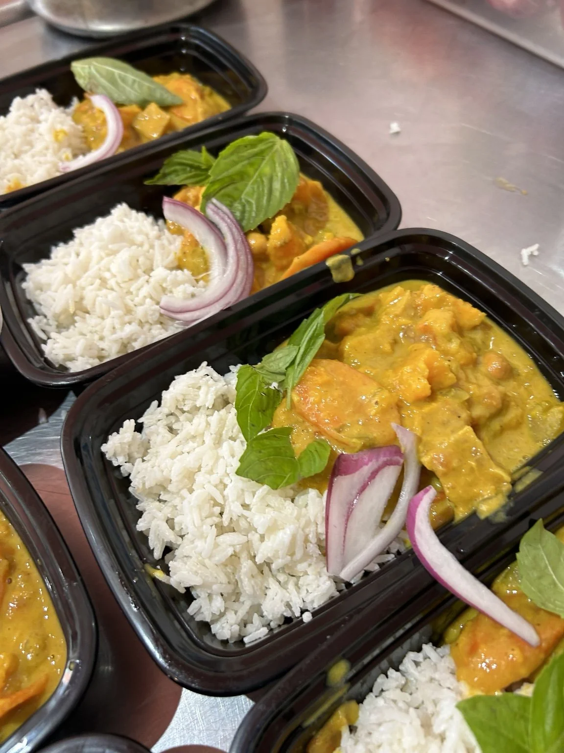 Curry and rice meals garnished with fresh herbs and red onion.