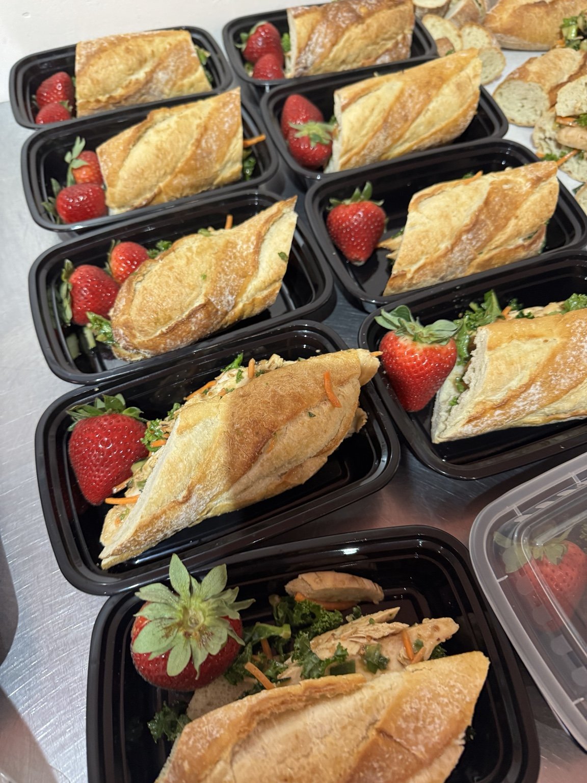 Baguette sandwiches paired with strawberries in individual containers.