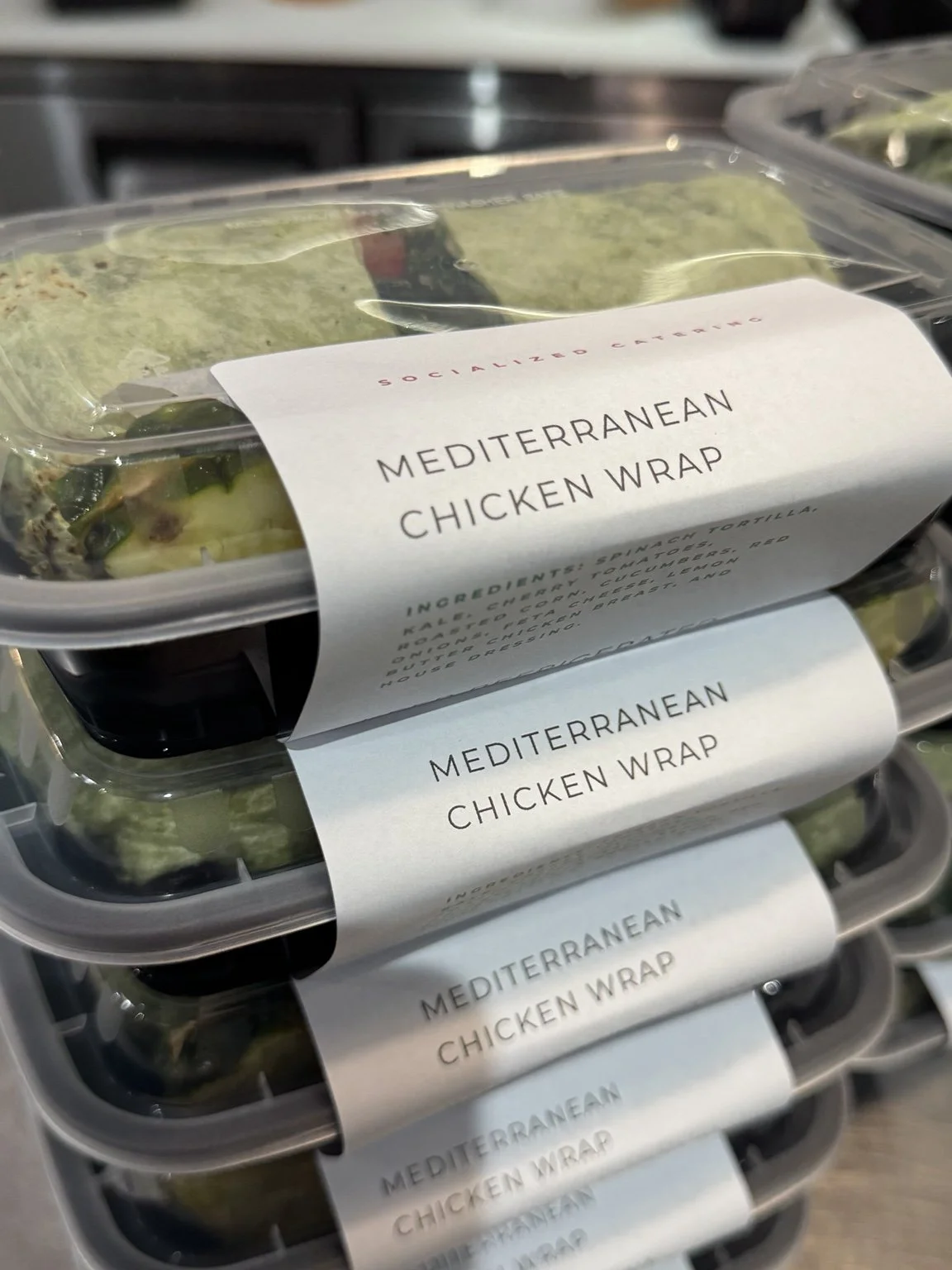 Mediterranean chicken wraps packed with Socialized Catering labels.