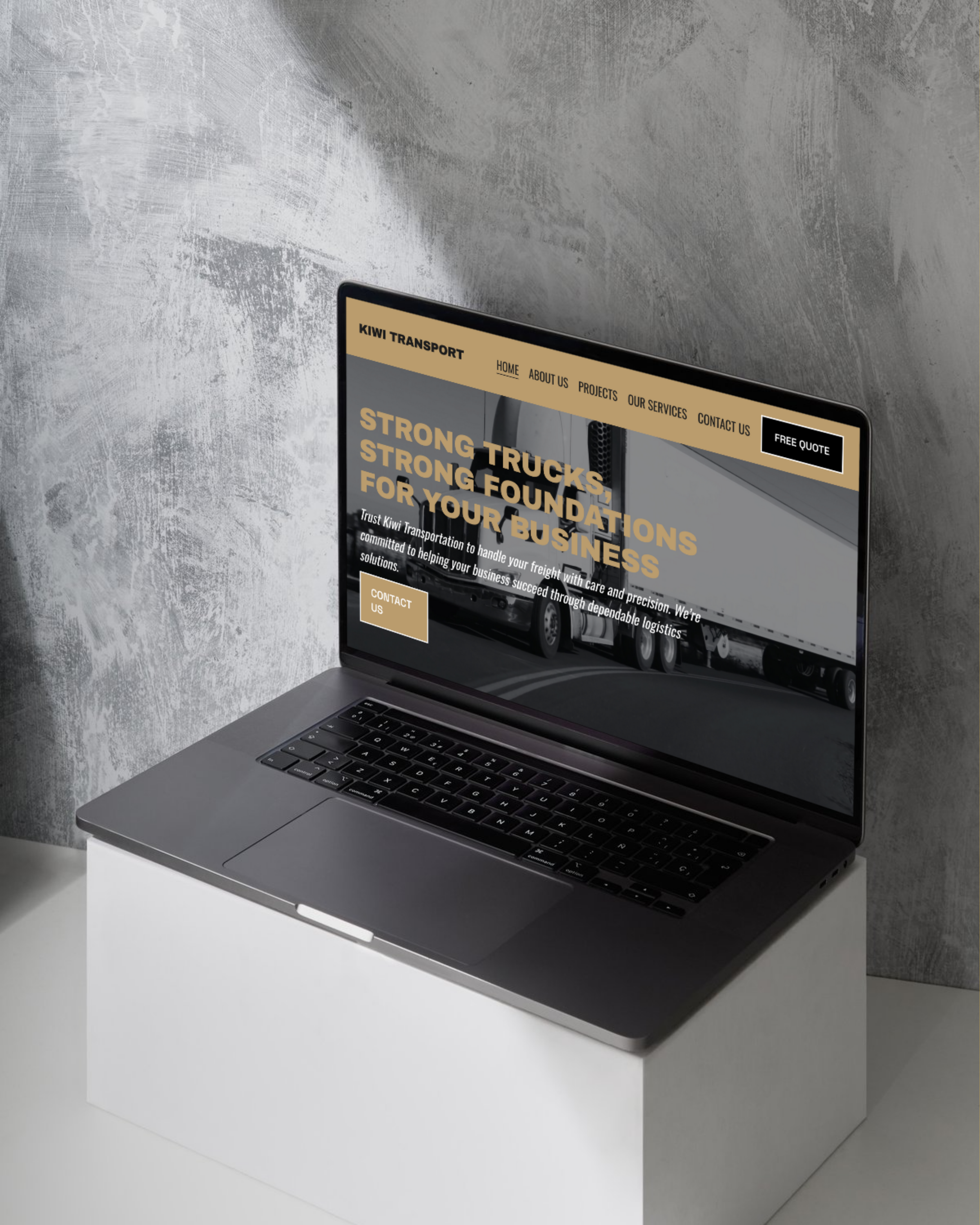 Laptop on a white pedestal displaying a transportation company website with truck images, bold text, navigation menu, and a contact button.