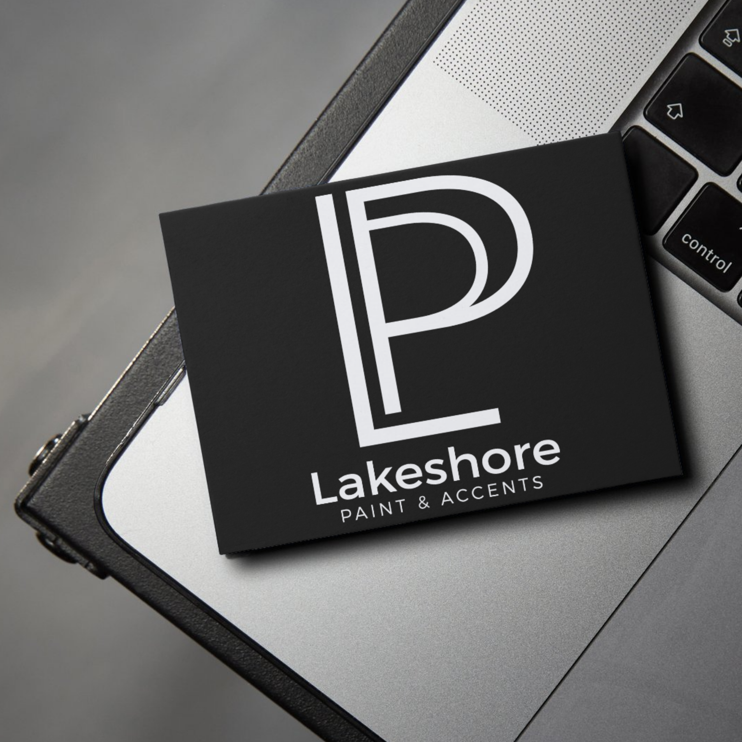 Black branded card for Lakeshore Paint & Accents on a laptop keyboard.