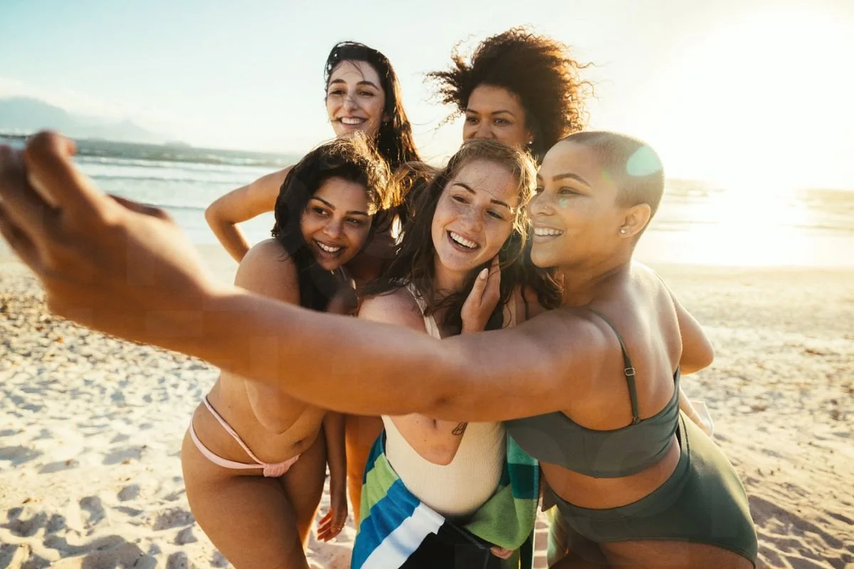 Group of friends enjoying a sunny beach day while staying active during the summer.