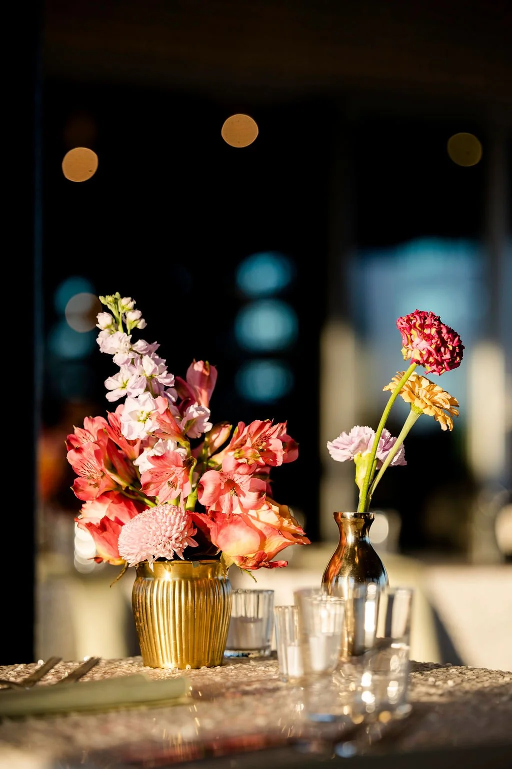 Wedding guest table with bright floral bud vases.