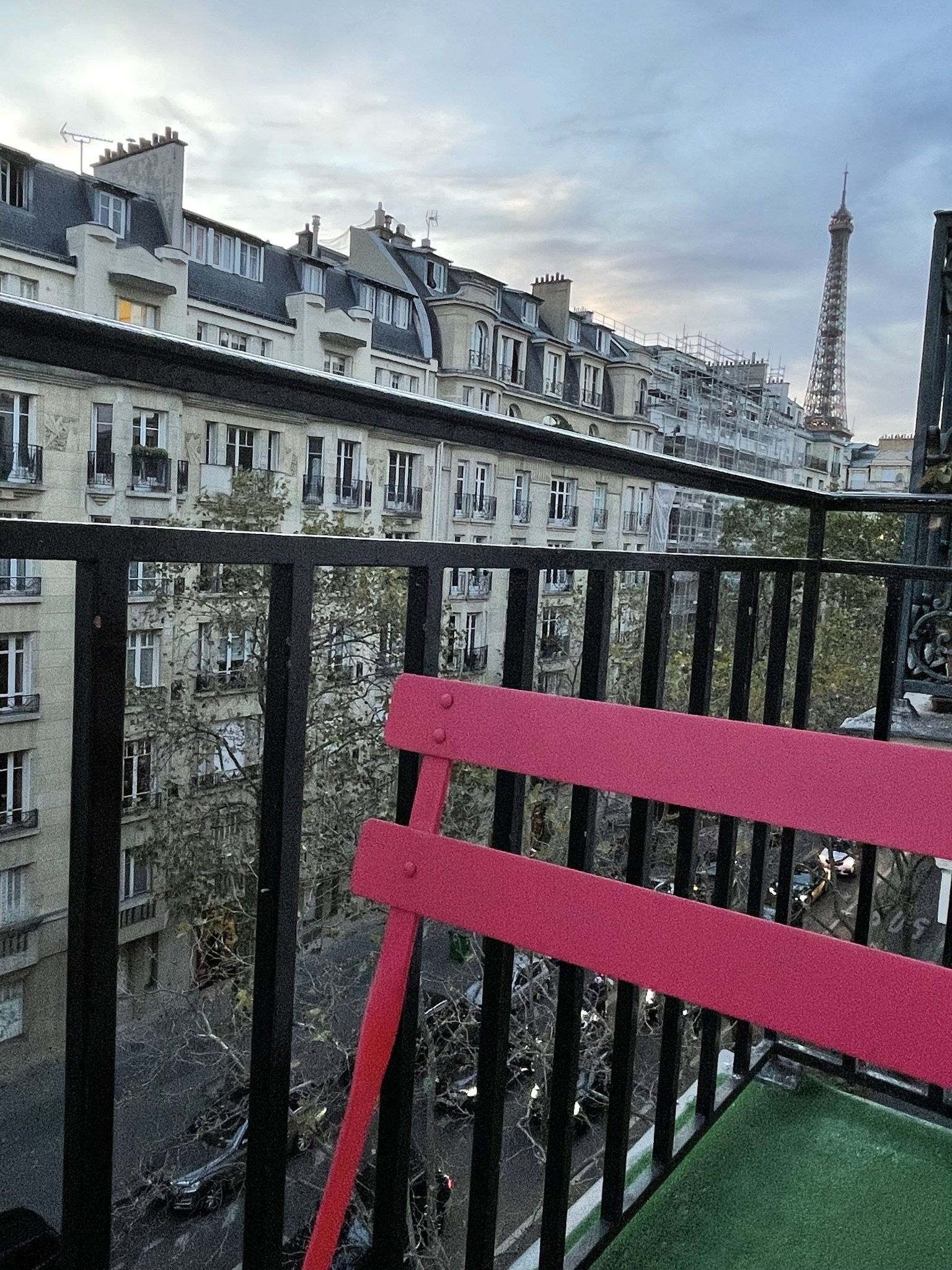 Parisian architecture and the Eiffel Tower in the distance under a cloudy sky.