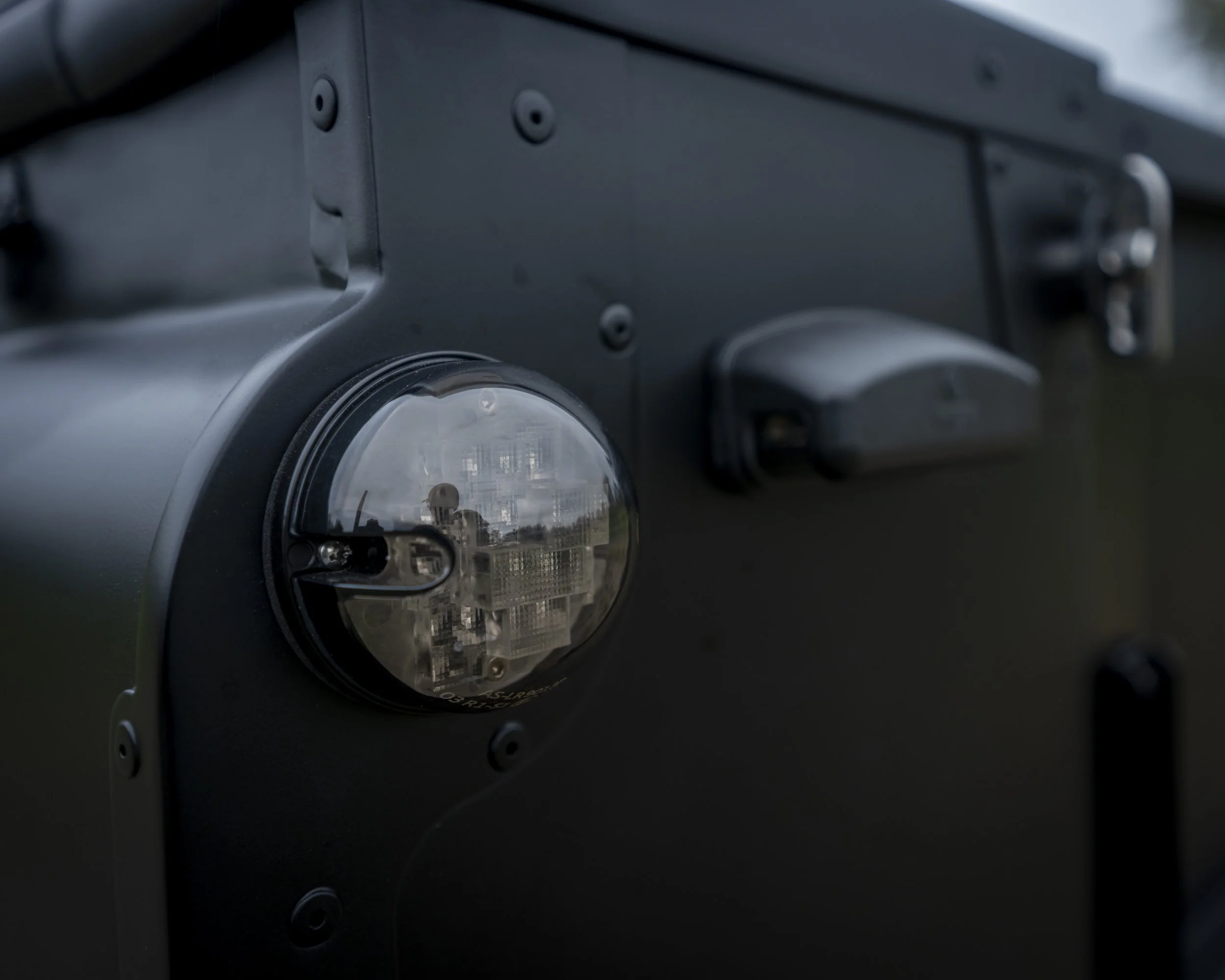 Close-up of a black electronic device with a clear, rounded cover revealing internal components, possibly a sensor or camera, mounted on a dark surface.