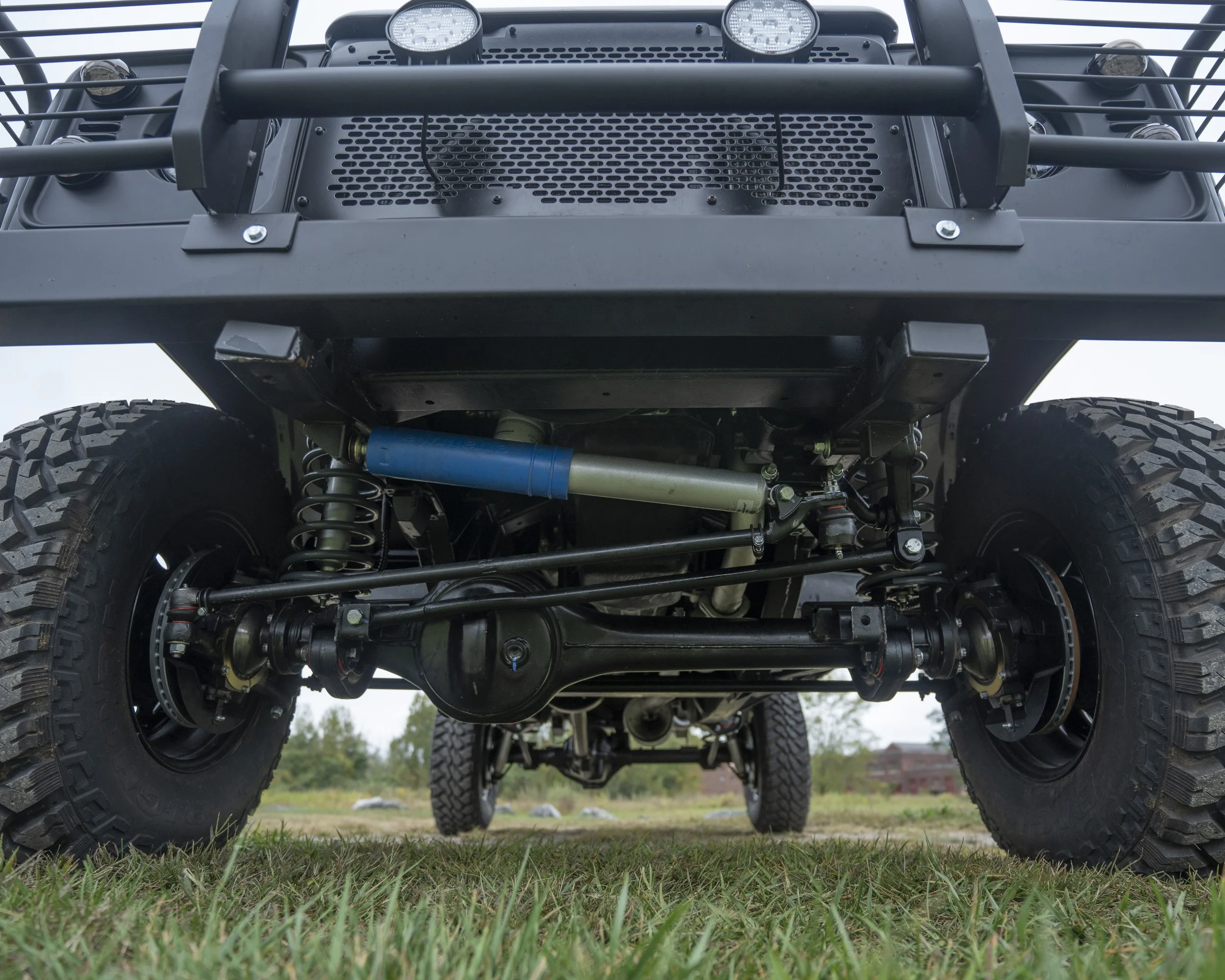View of the underside of a rugged off-road vehicle showing suspension and tires.