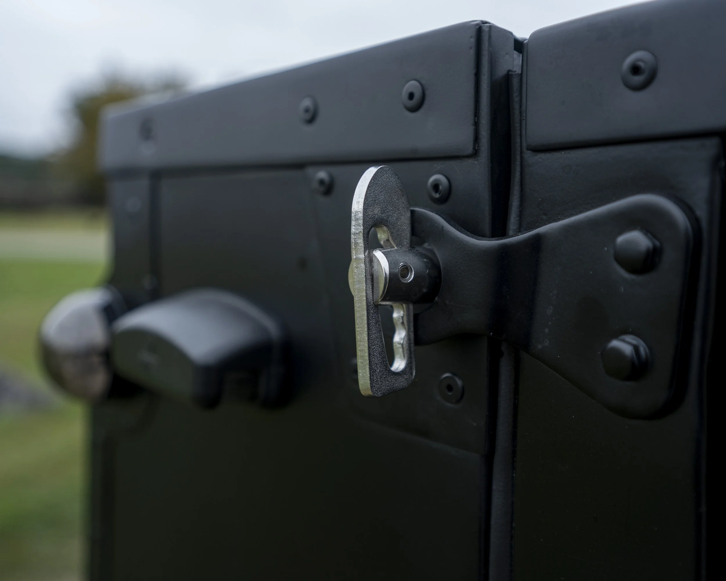 Close-up of a black metal electrical enclosure with a padlock latch and a silver key inserted in the lock.