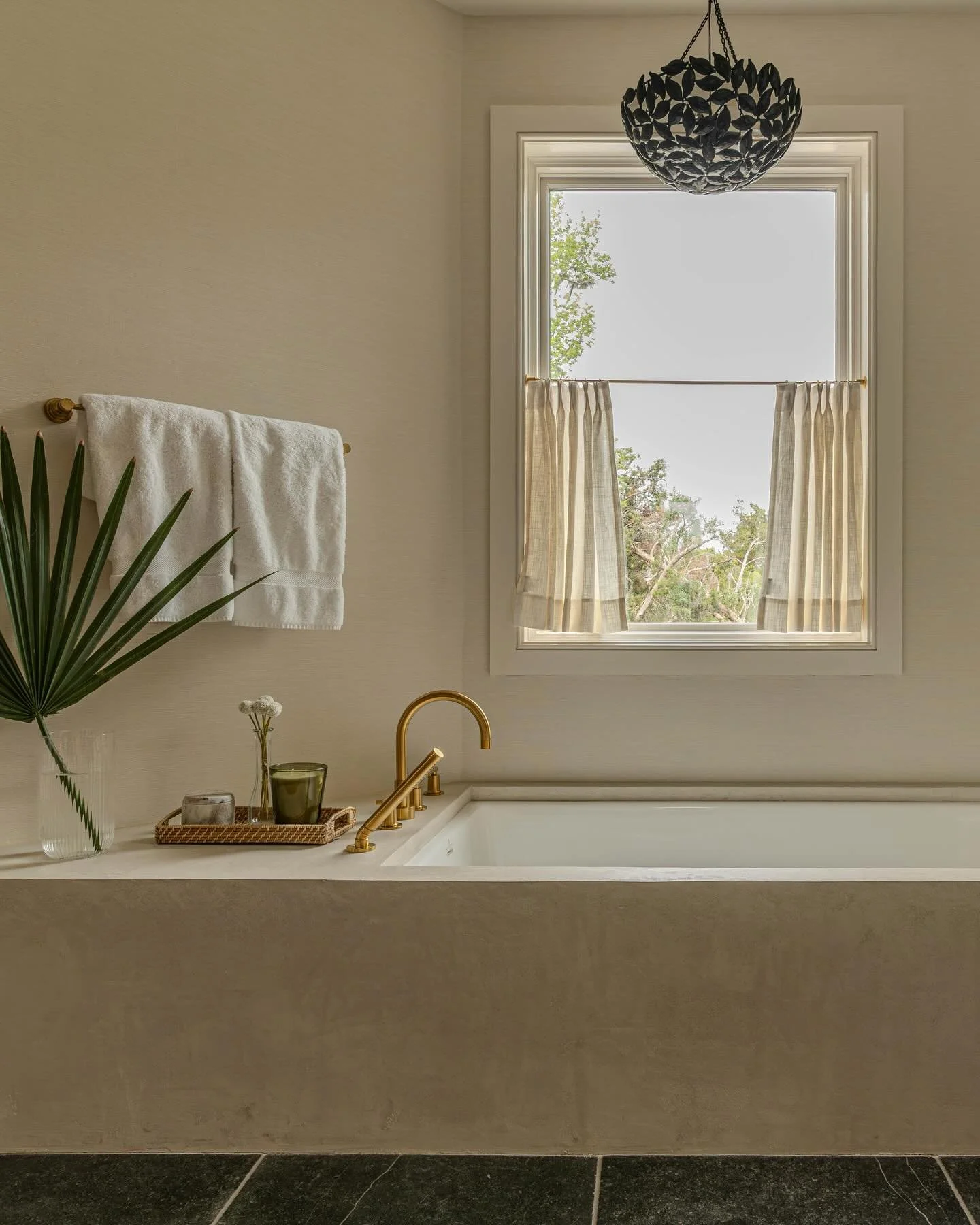 Peace + Quiet. This primary bathroom is layered with warm and inviting materials. From the plater tub surround and the grasscloth wallcovering to the brushed brass plumbing.  The space is grounded by tumbled slate floors and accented with an iron @vi