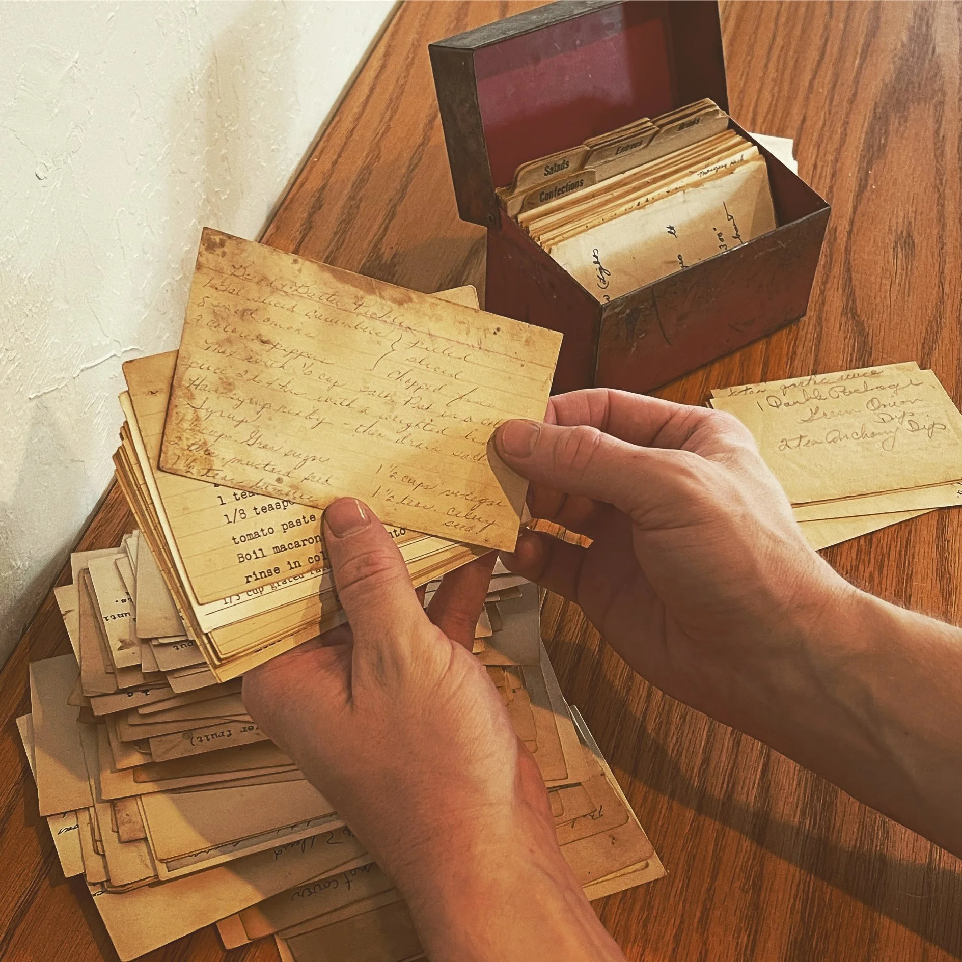 Hands lodging lots of old style recipe cards and a recipes boc