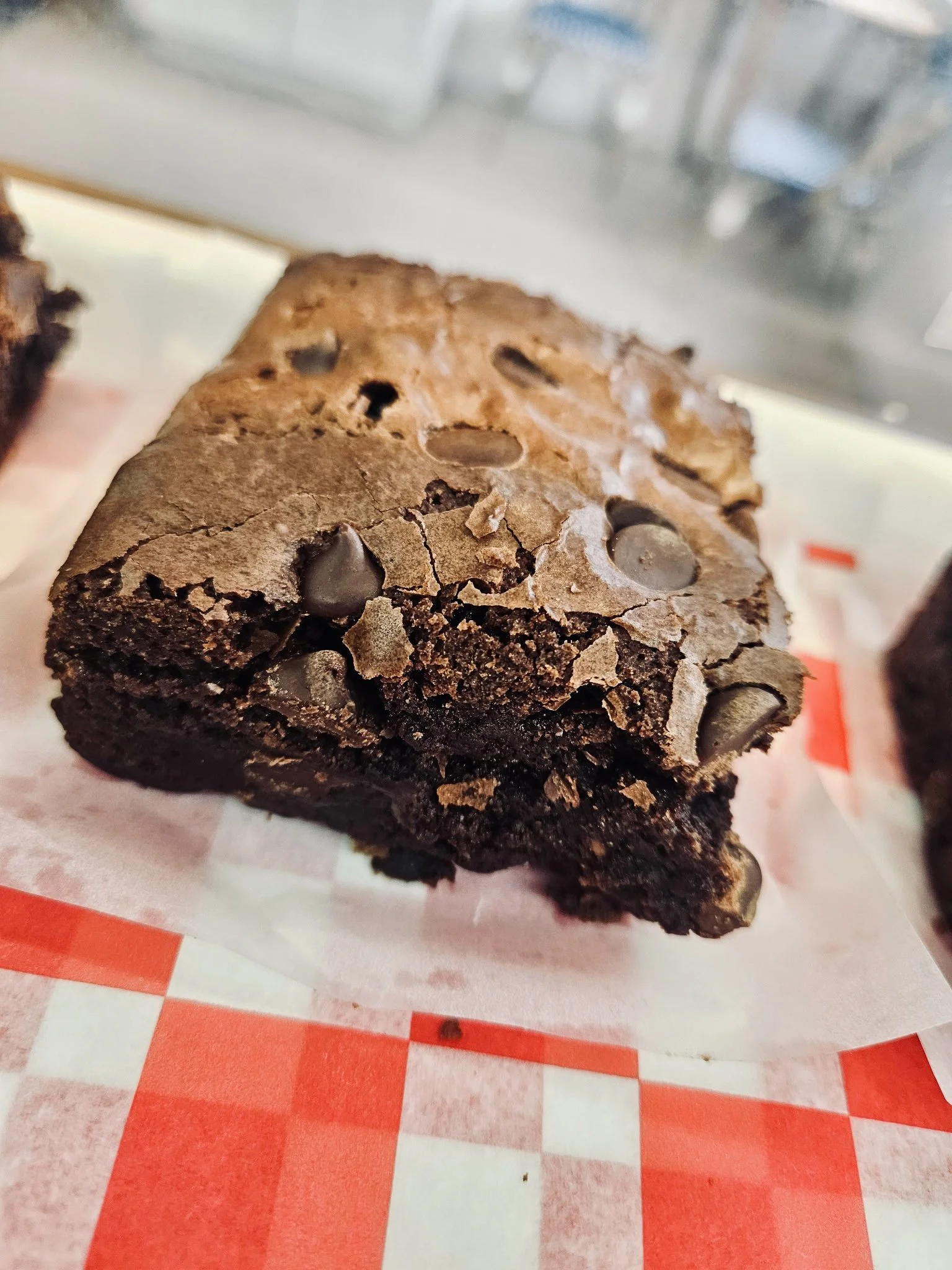 A chocolate chip brownie on red check paper