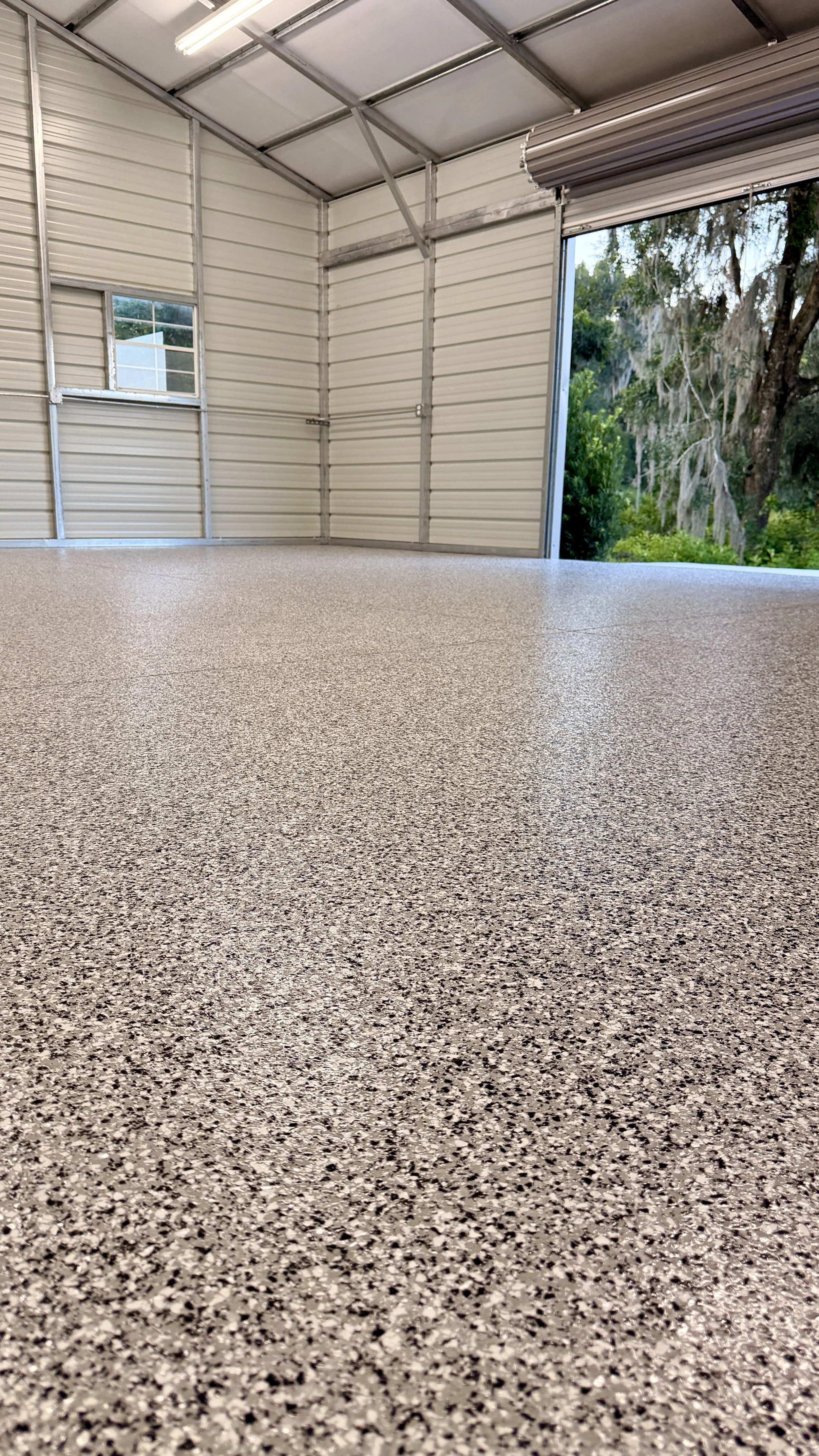 A picture of a detached garage with a new epoxy floor coating with a polyaspartic top coat.
